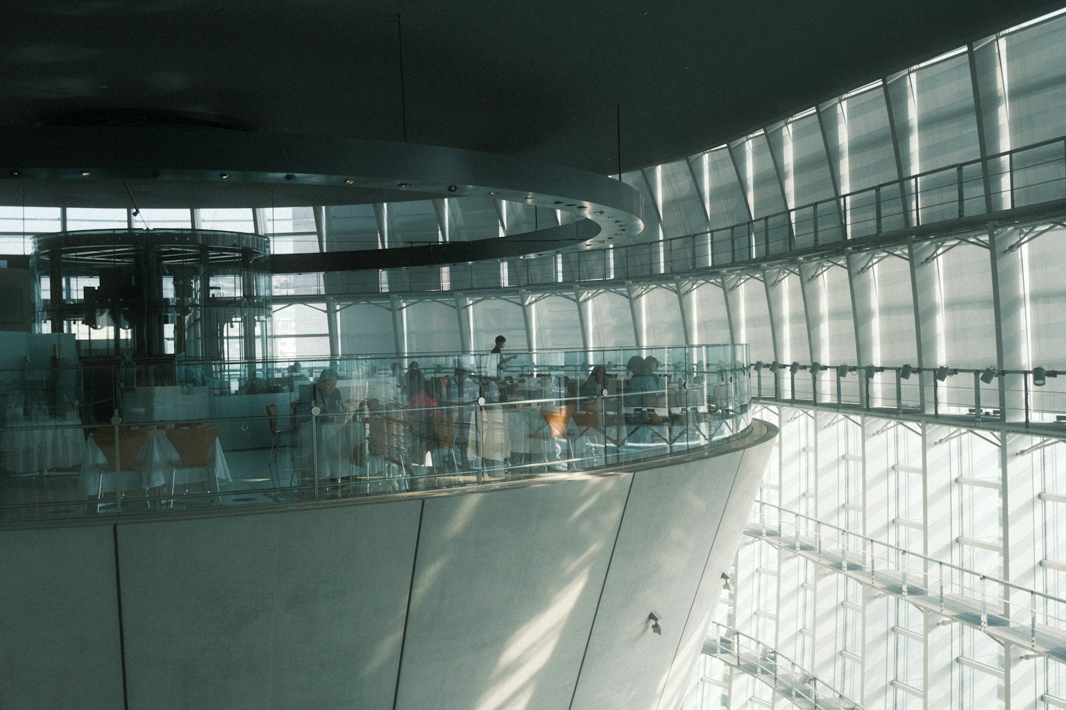Interior of a modern architectural space featuring large windows and a curved balcony with natural light