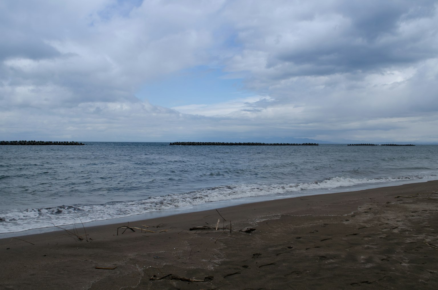 Vue de la mer et de la plage de sable sous un ciel nuageux avec des vagues douces