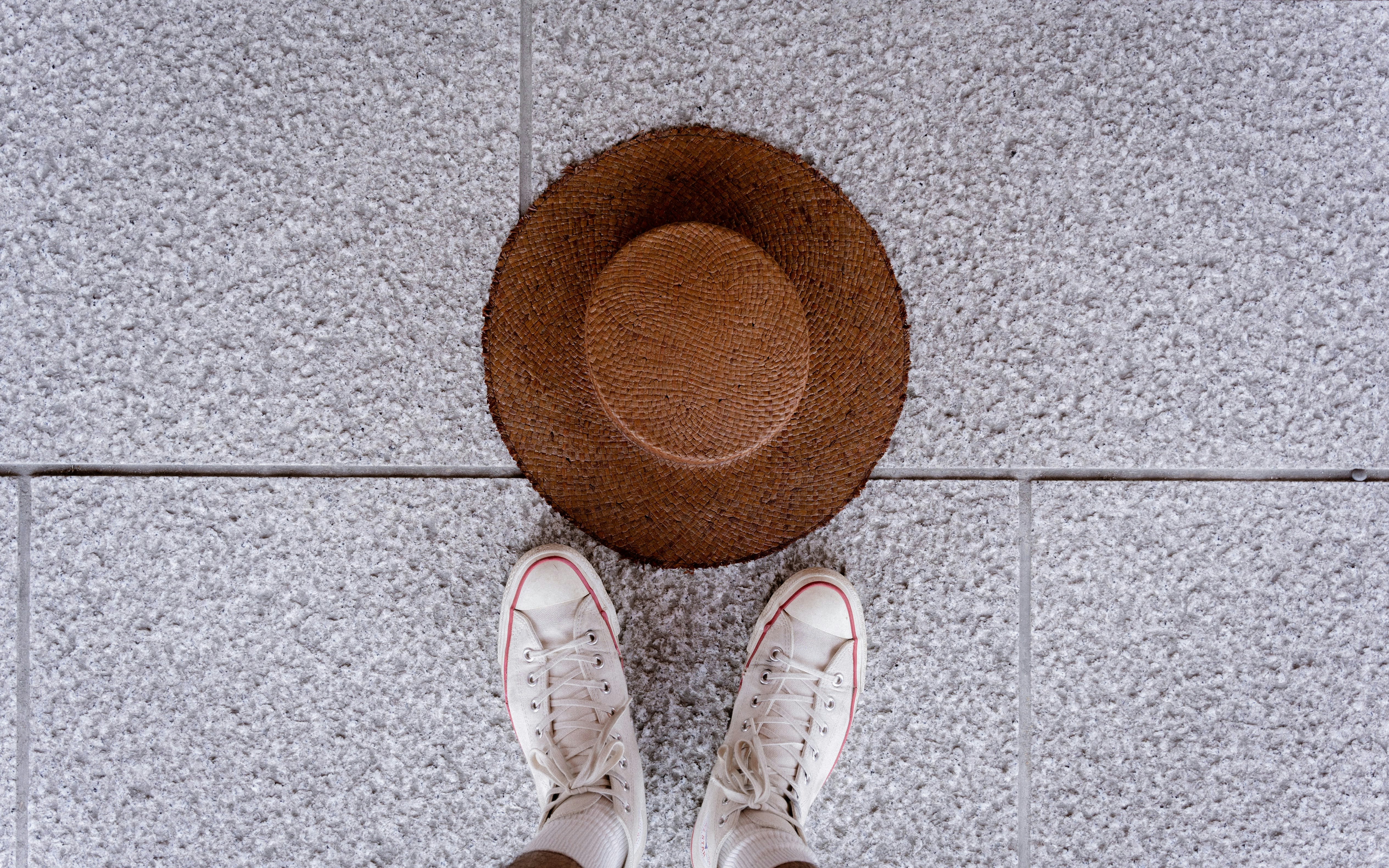 straw hat and white sneakers on a tiled entryway