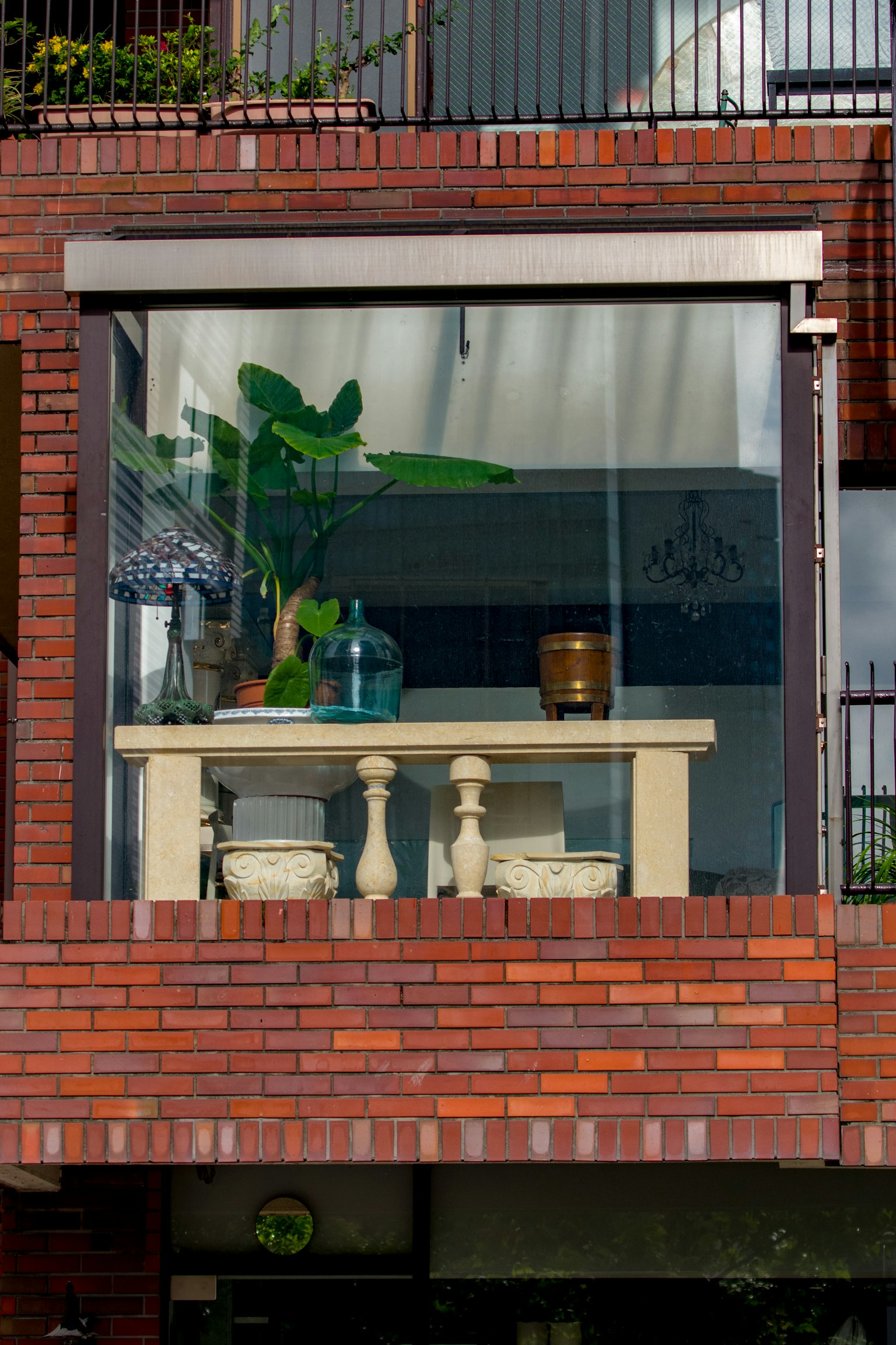 Glasbalkon mit Tisch und Stühlen umgeben von Pflanzen und Dekorationsobjekten