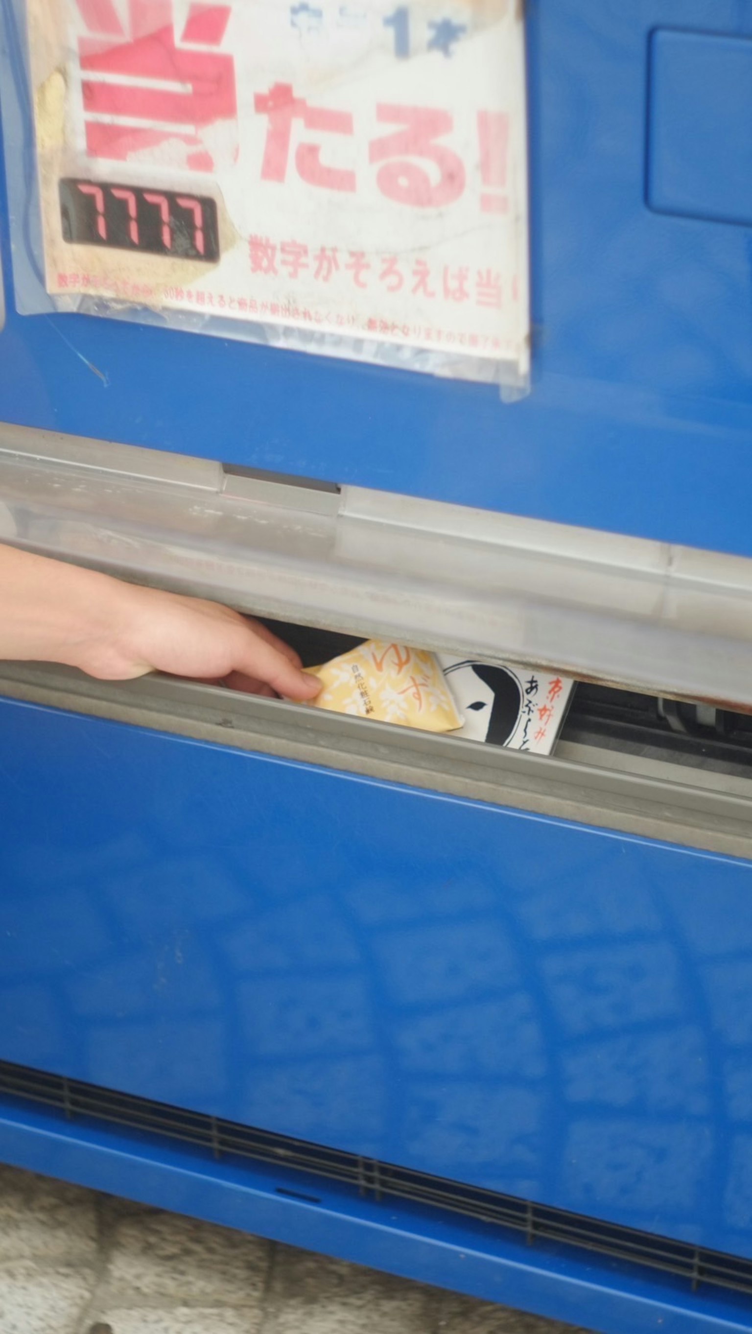 A hand reaching into a blue vending machine