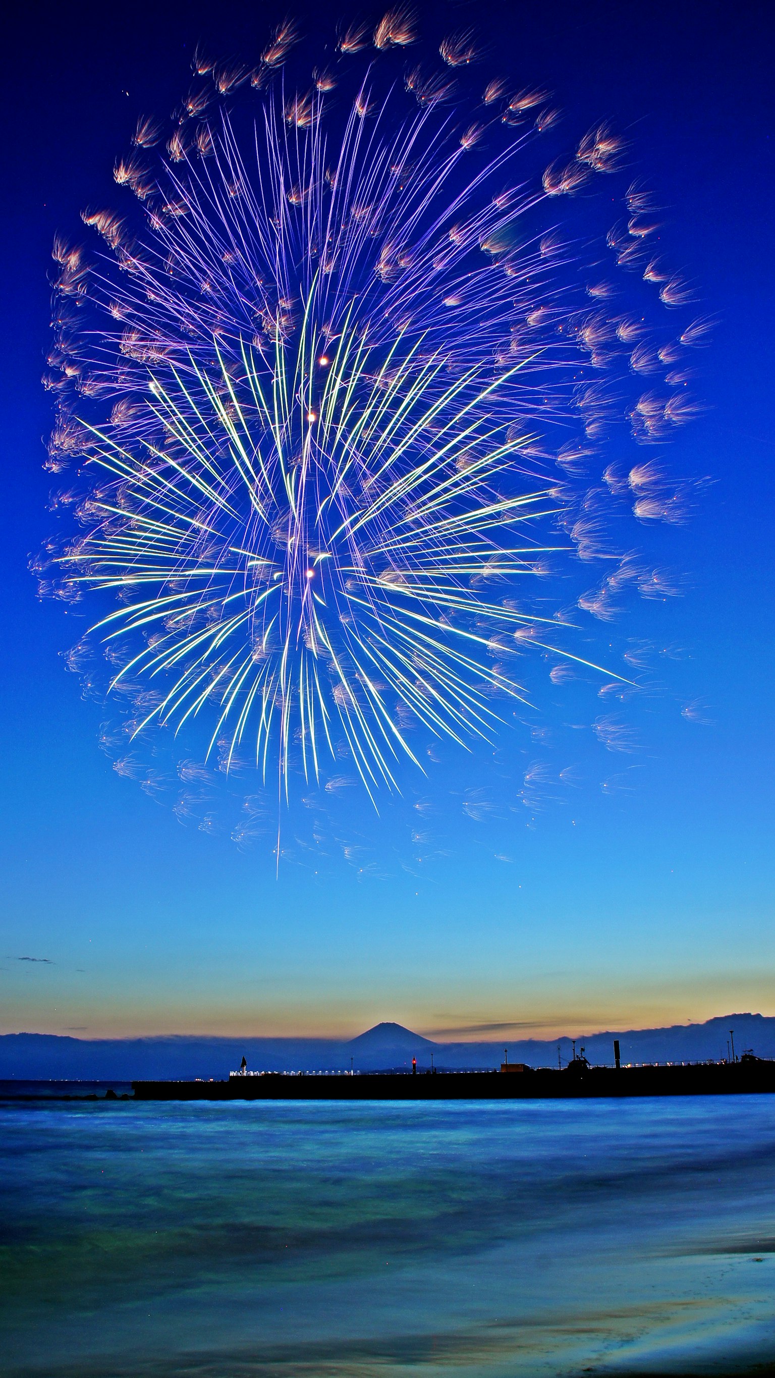 Spettacolo di fuochi d'artificio colorati sopra l'oceano al crepuscolo