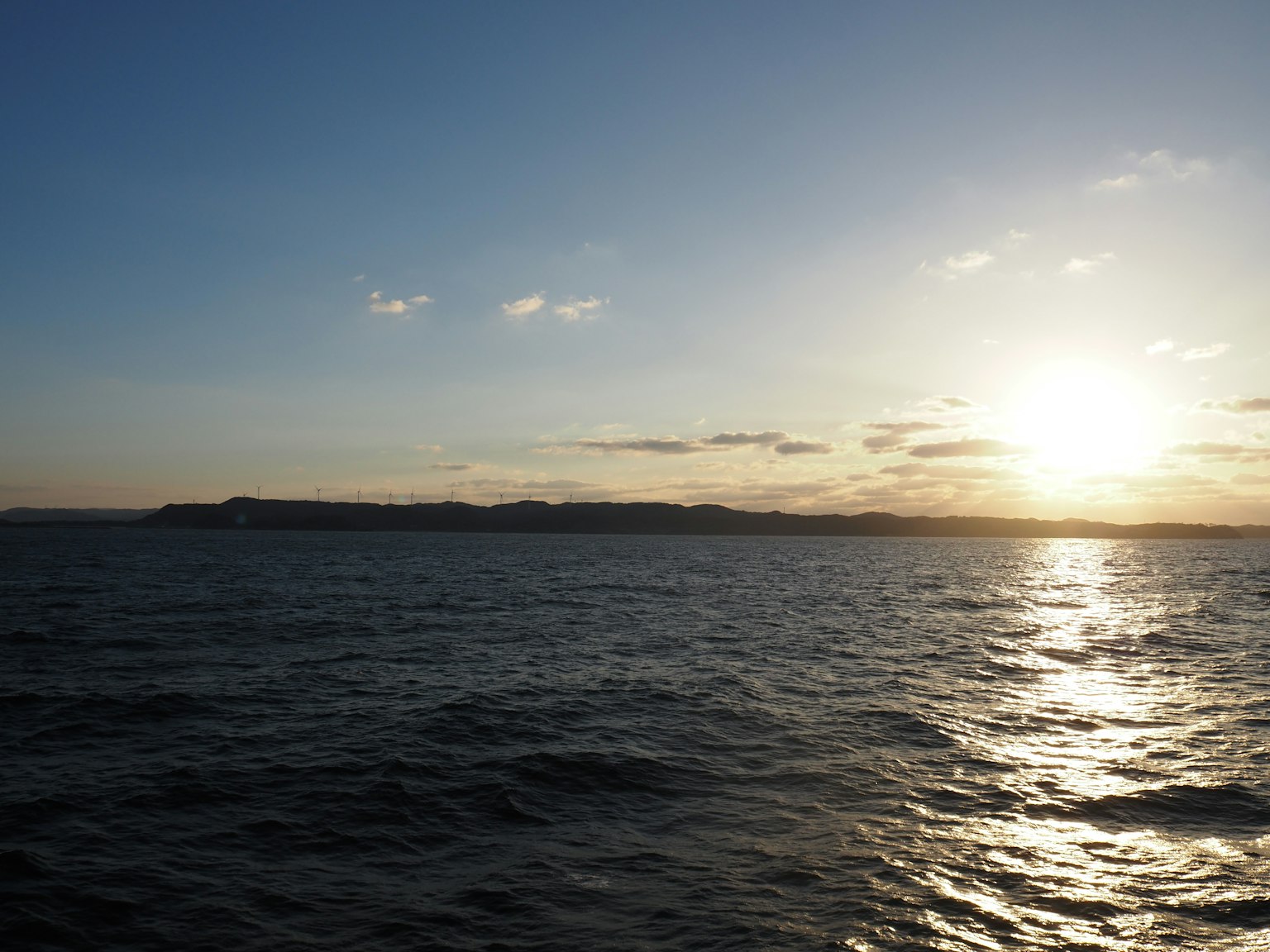 Tramonto sul mare calmo con terra lontana