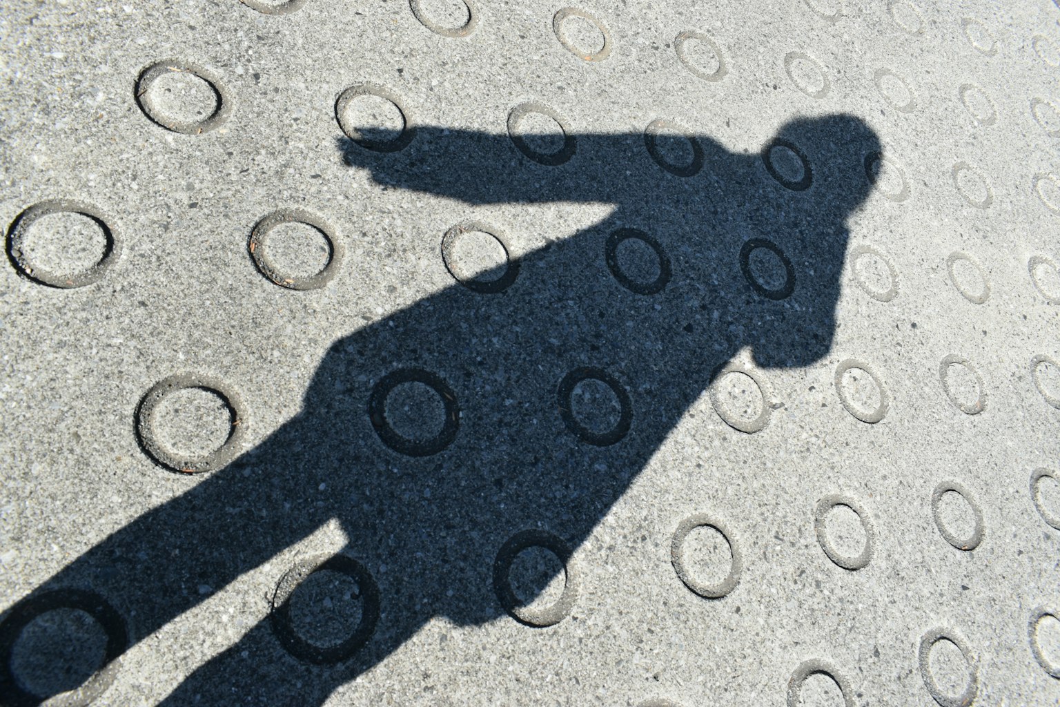 Shadow of a person cast on a textured surface with circular patterns