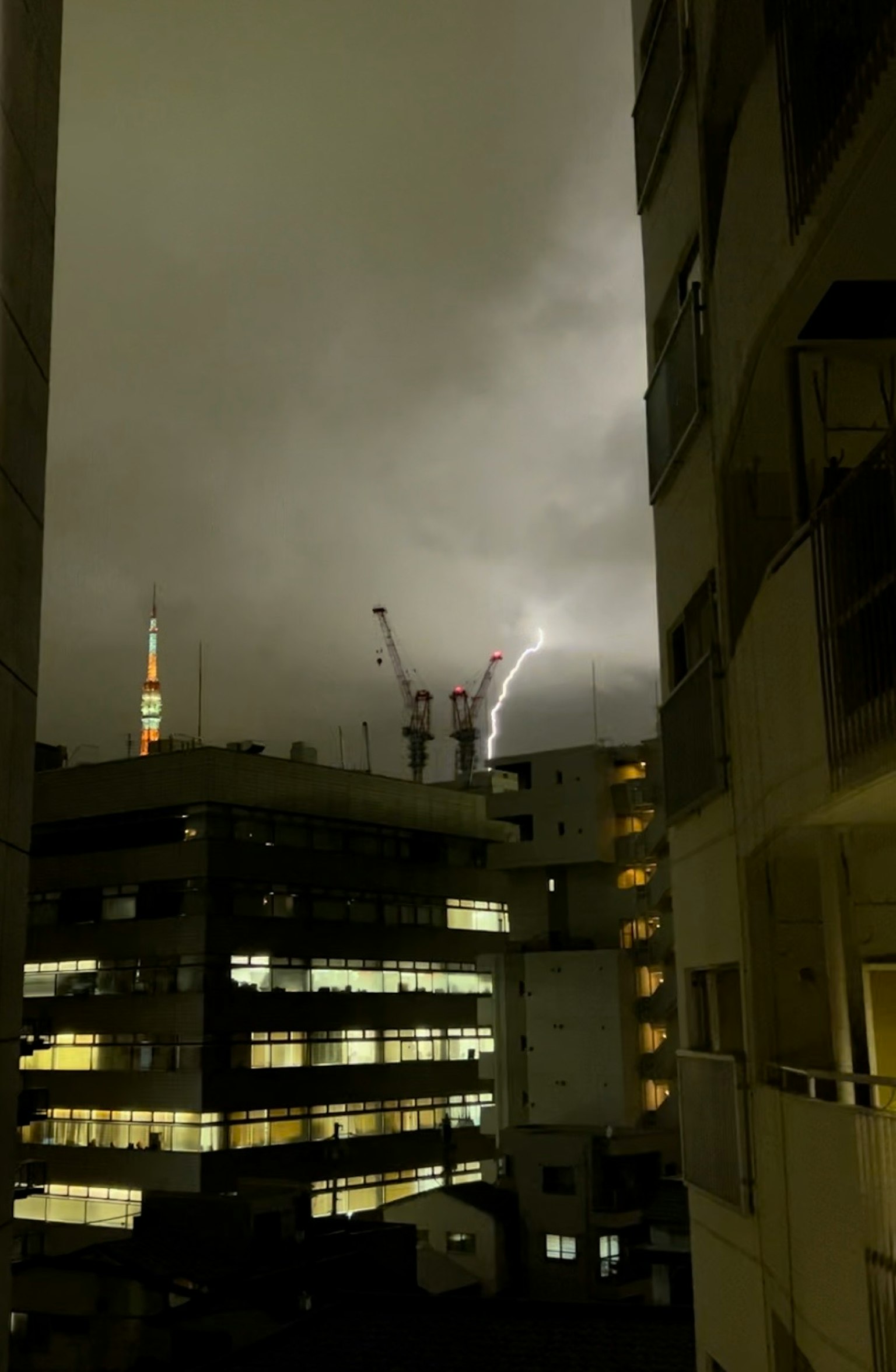 Vista notturna con fulmine che colpisce un edificio e nuvole scure