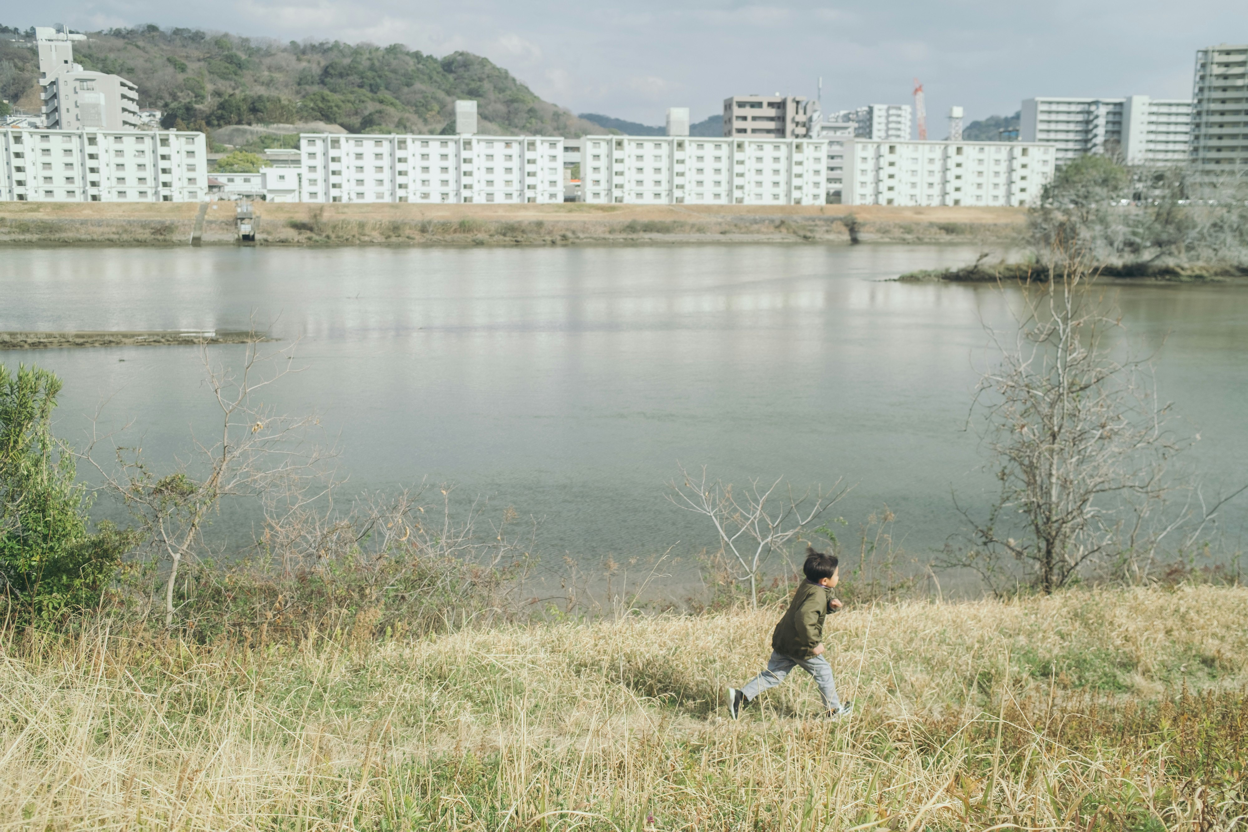 川のそばで走る子供と背景の建物