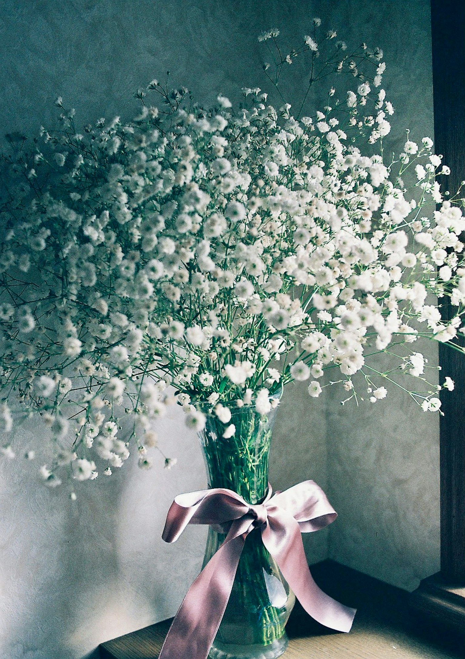 Ein Strauß kleiner weißer Blumen in einer Vase mit einem rosa Band gebunden