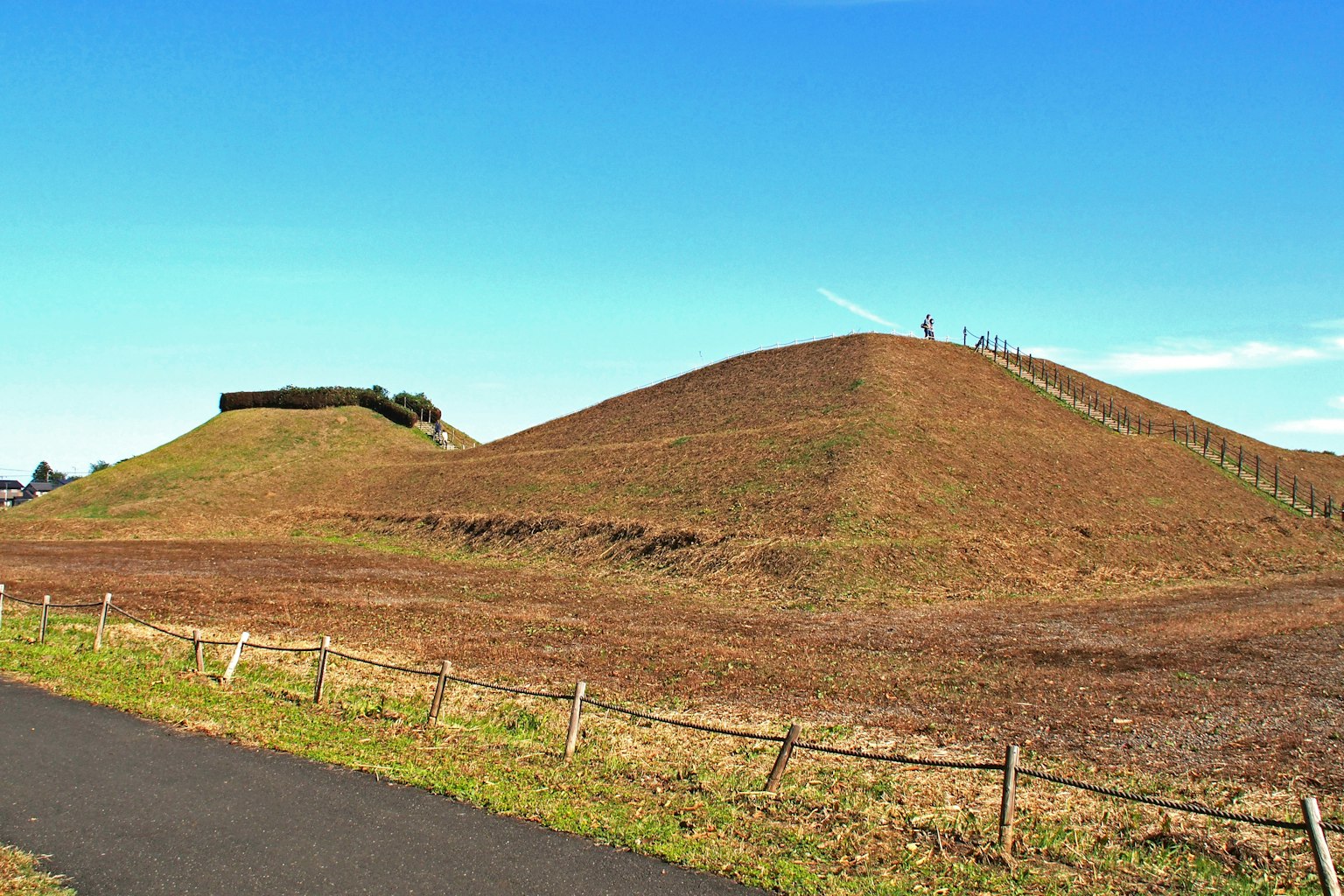 Landschaft mit grasbewachsenen Hügeln unter blauem Himmel