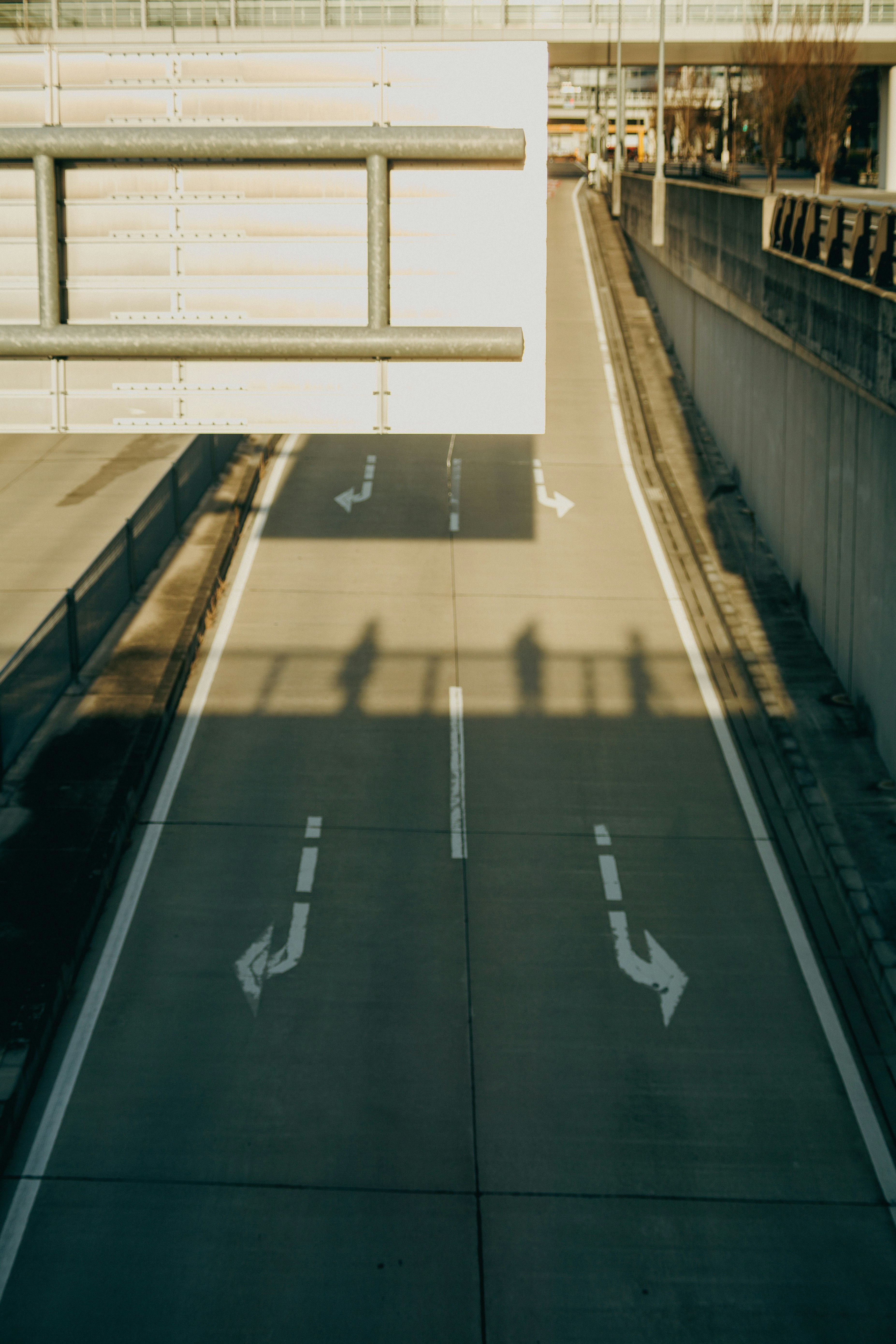 straight urban road under an elevated structure with sidewalks