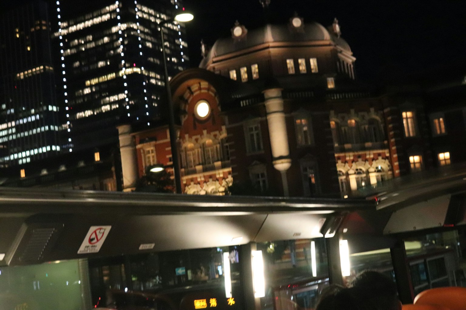 Vista nocturna de la estación de Tokio con rascacielos modernos de fondo