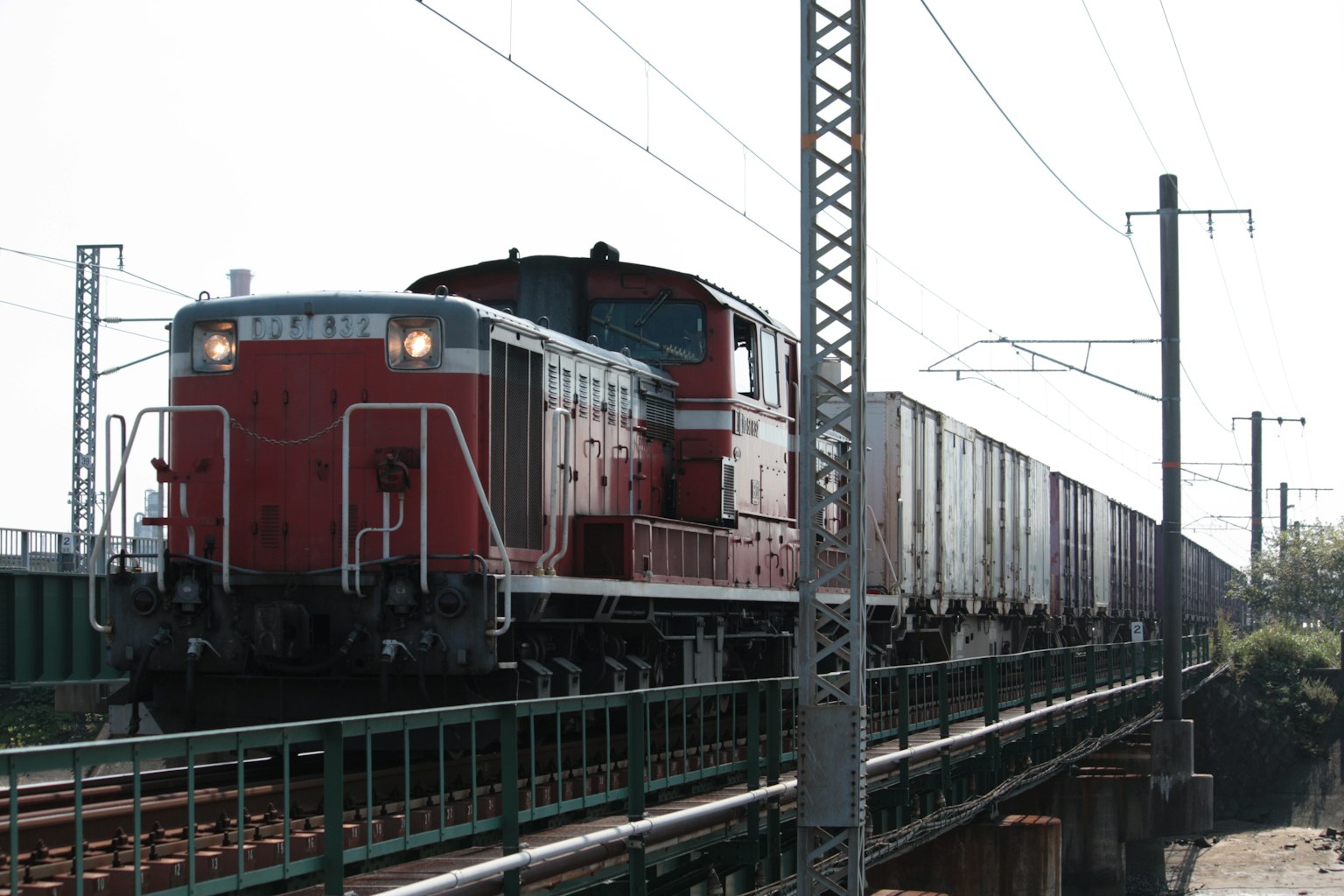 Un tren de carga rojo que se mueve sobre un puente