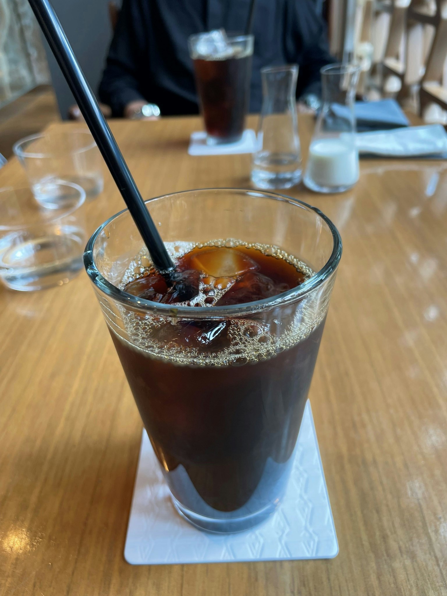 一杯冰咖啡放在木桌上,配有黑色吸管