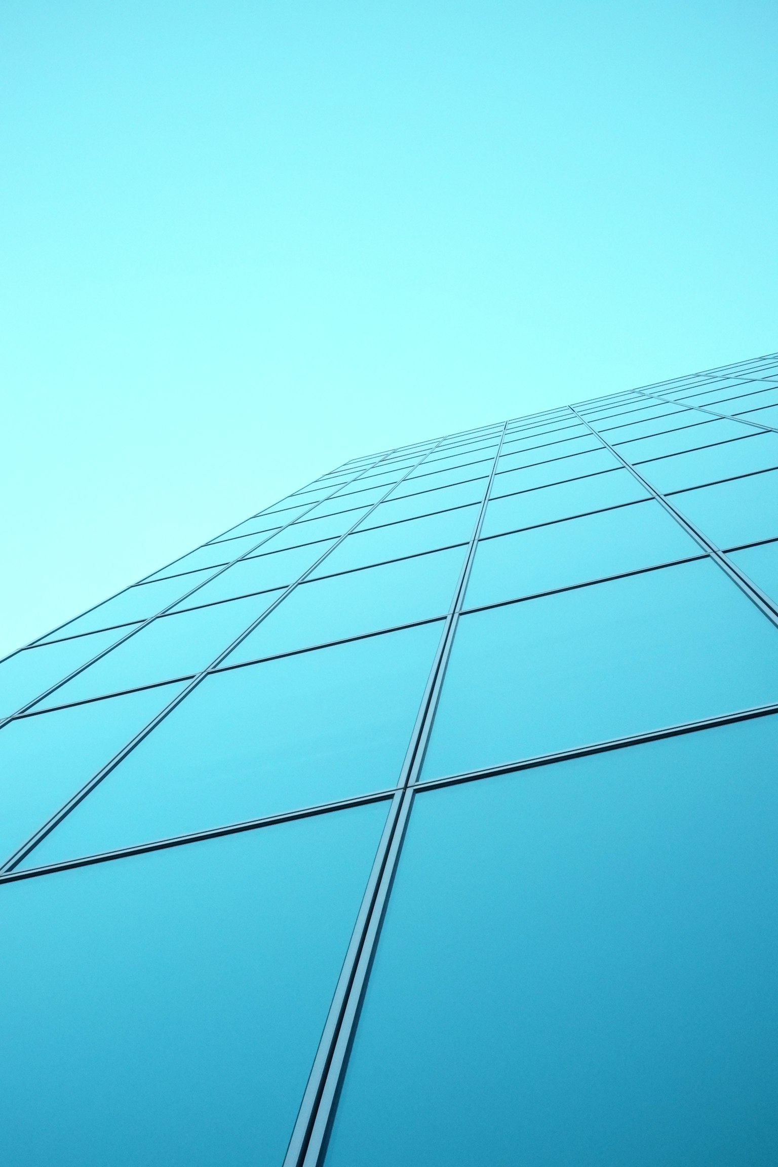 Moderne Glasgebäudefassade vor blauem Himmel