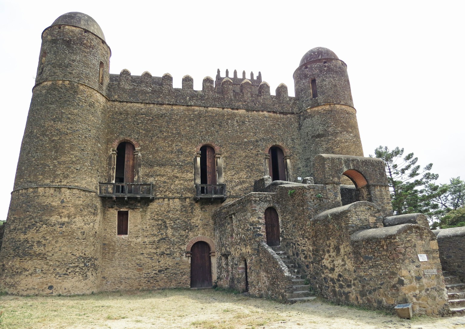Extérieur d'un vieux château en pierre avec des tours et des escaliers