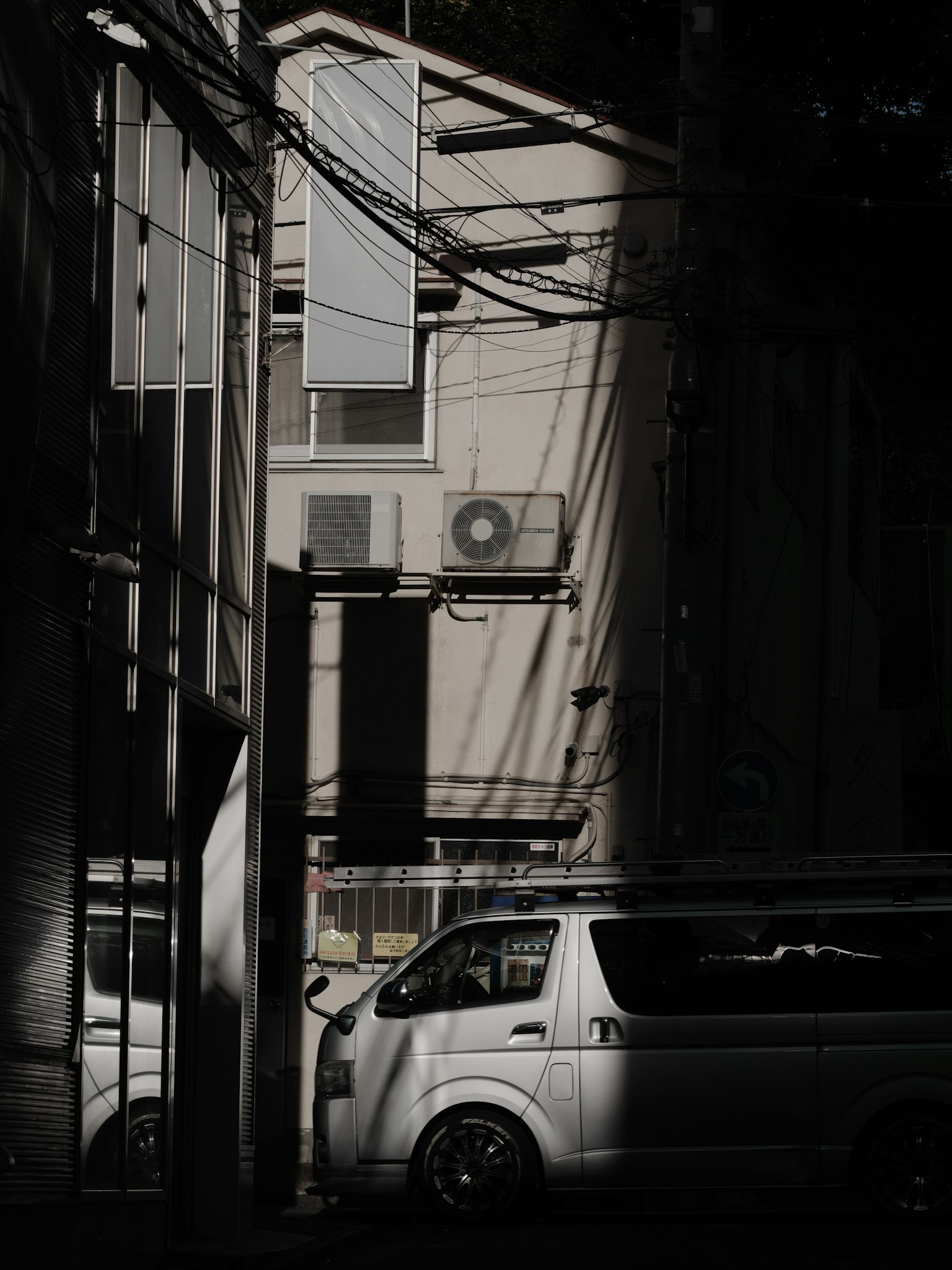 Urban scene with shadows on buildings and a white vehicle
