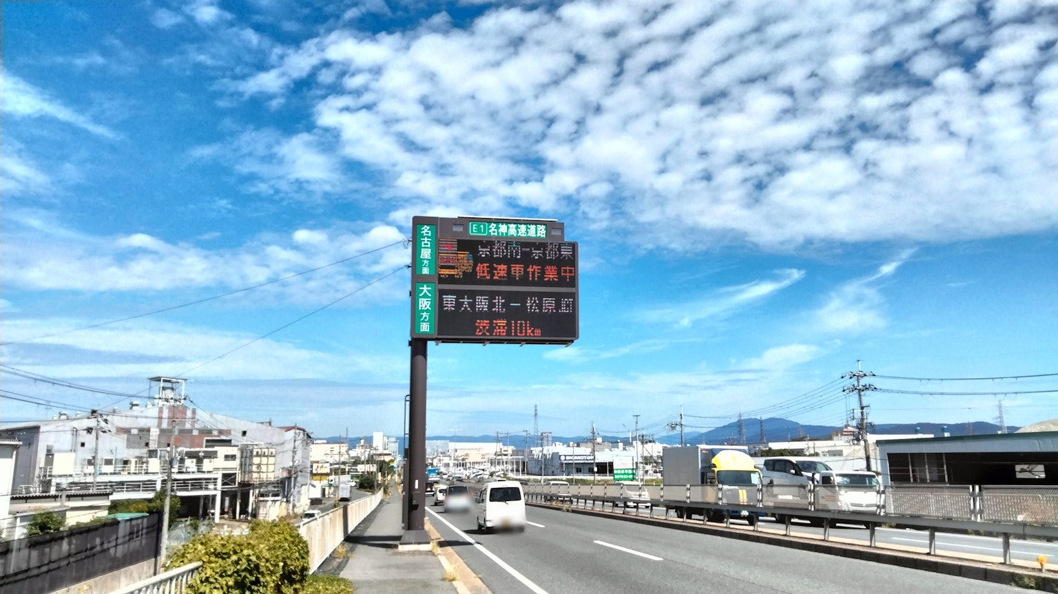 Scène de route avec panneau numérique sous un ciel bleu