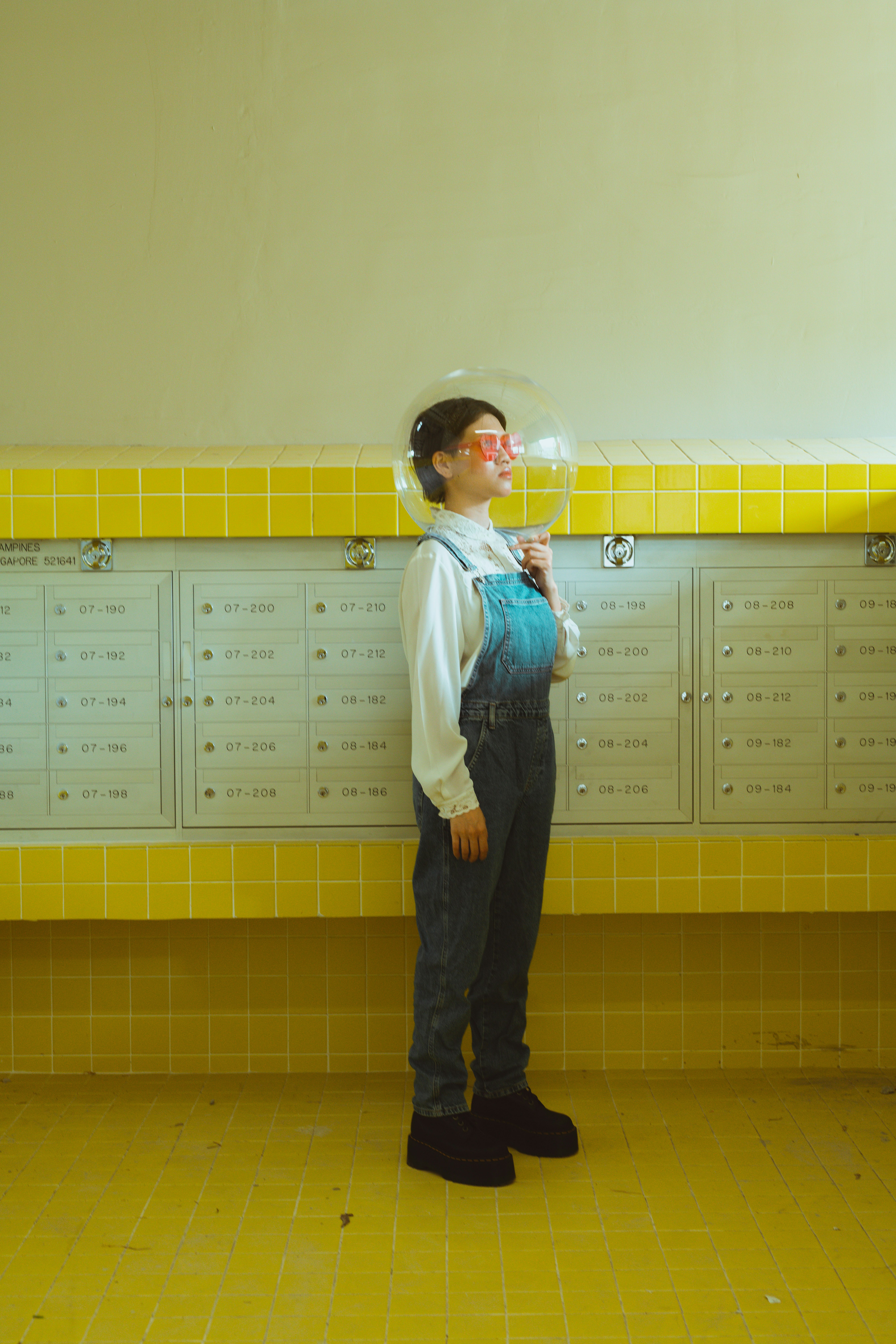 locker-room corner with a person wearing red glasses against yellow tiled walls
