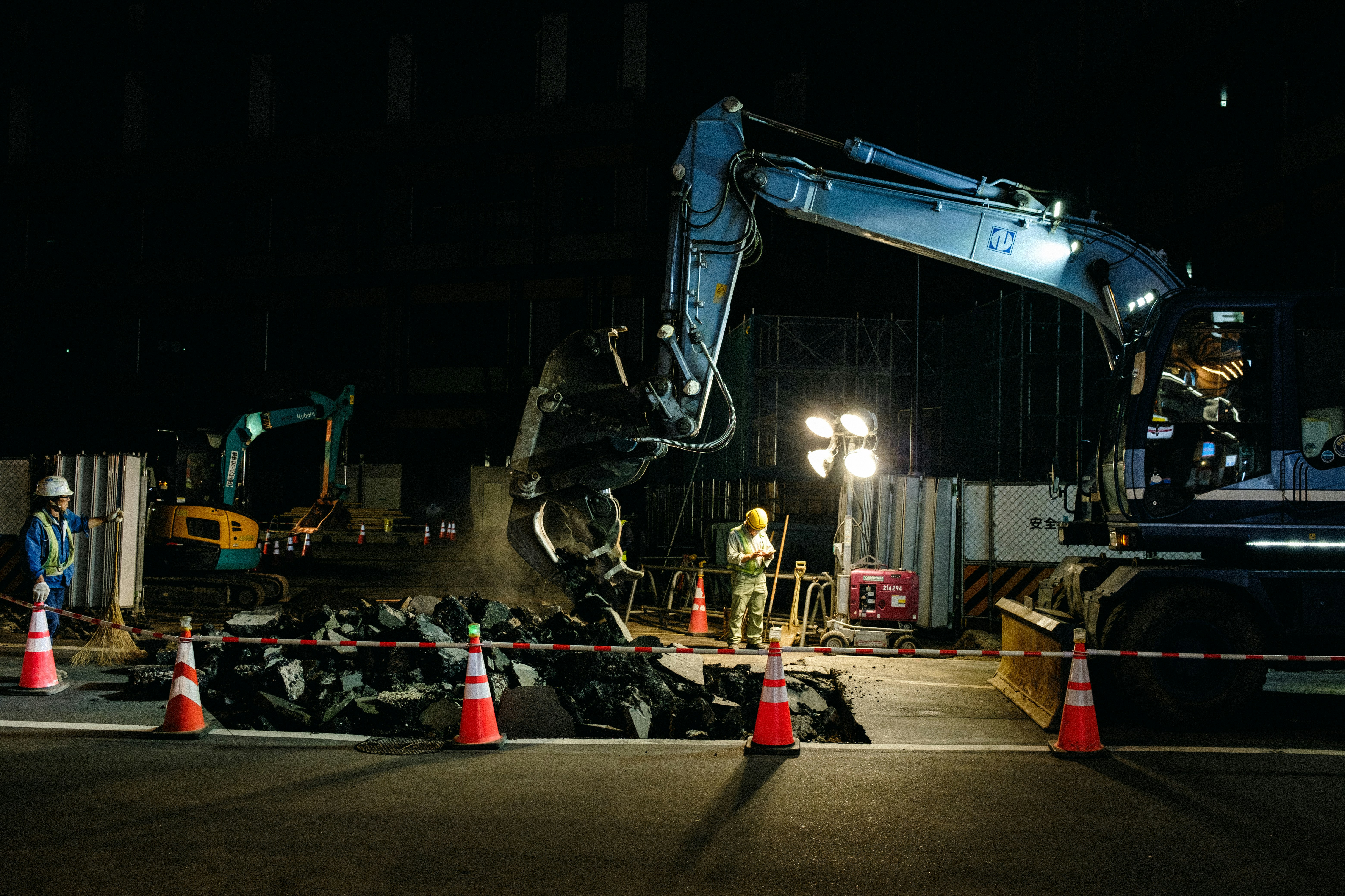 夜间道路施工现场，工人和重型机械