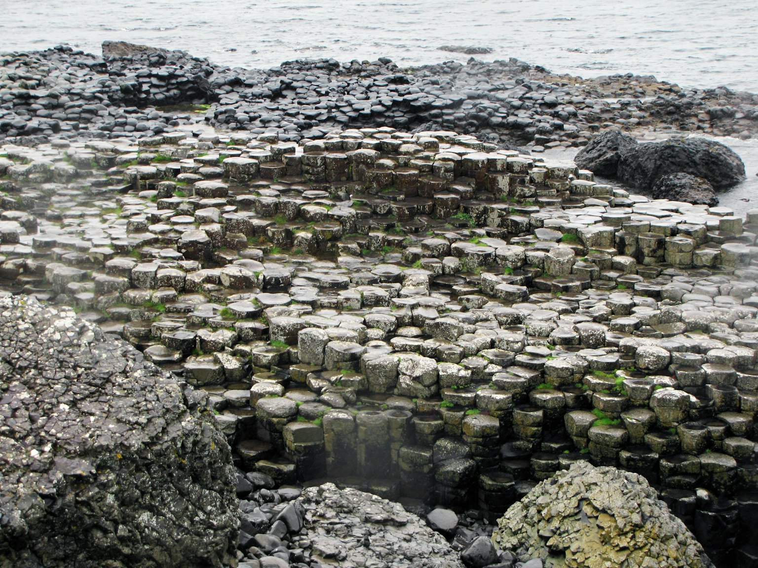 Sechseckige Steinformationen an einer felsigen Küste am Meer