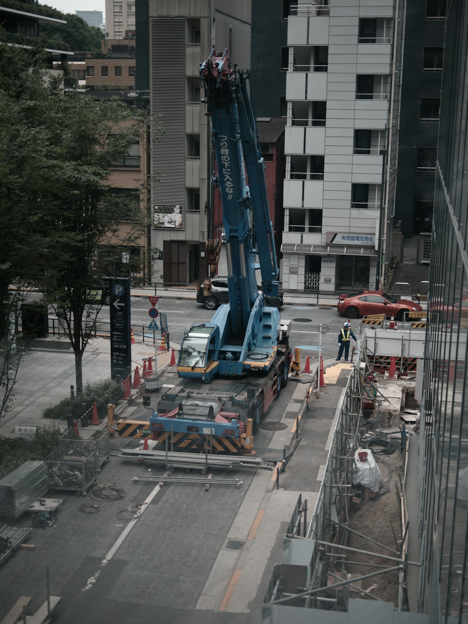 เครนสีน้ำเงินที่ไซต์ก่อสร้างพร้อมอาคารรอบข้าง