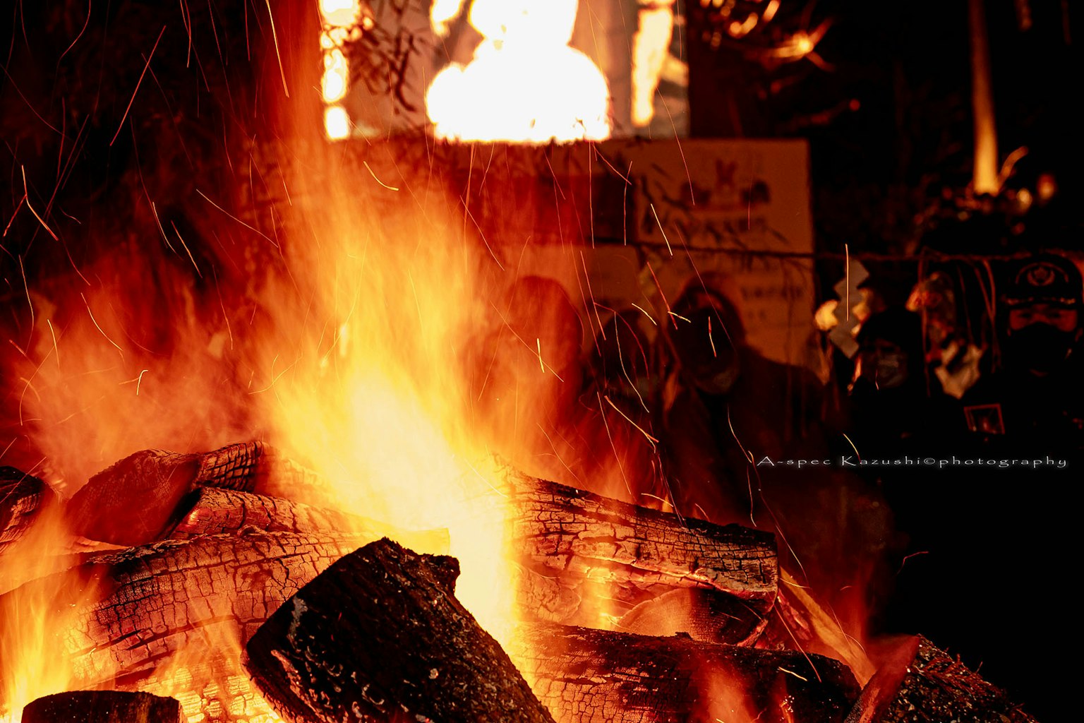 Eine Nahaufnahme eines lodernden Lagerfeuers mit brennenden Holzscheiten und glühenden Kohlen