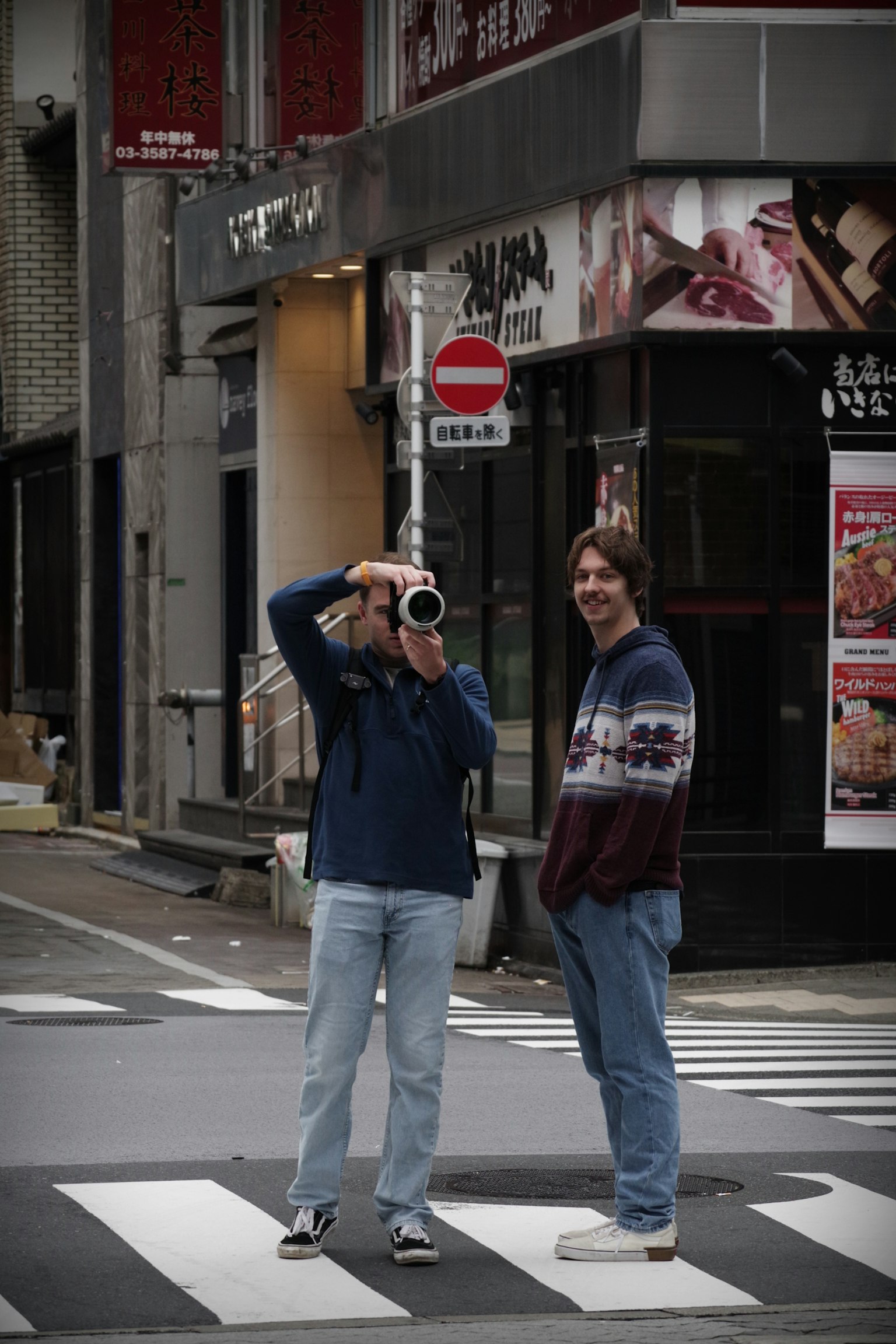 Foto di un uomo con una macchina fotografica e un altro uomo accanto a lui su un attraversamento pedonale