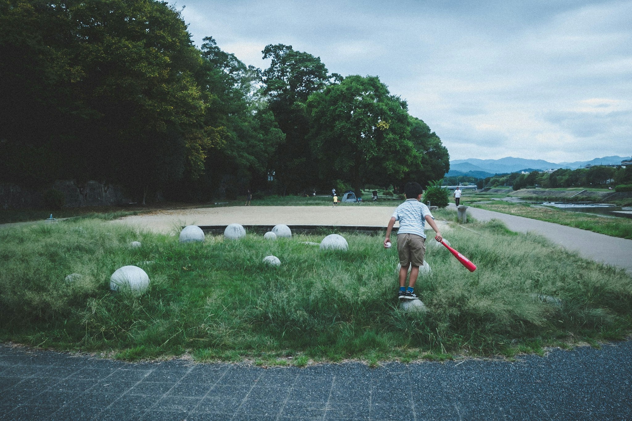 公园里草地小径上行走的人，周围有圆形修剪灌木