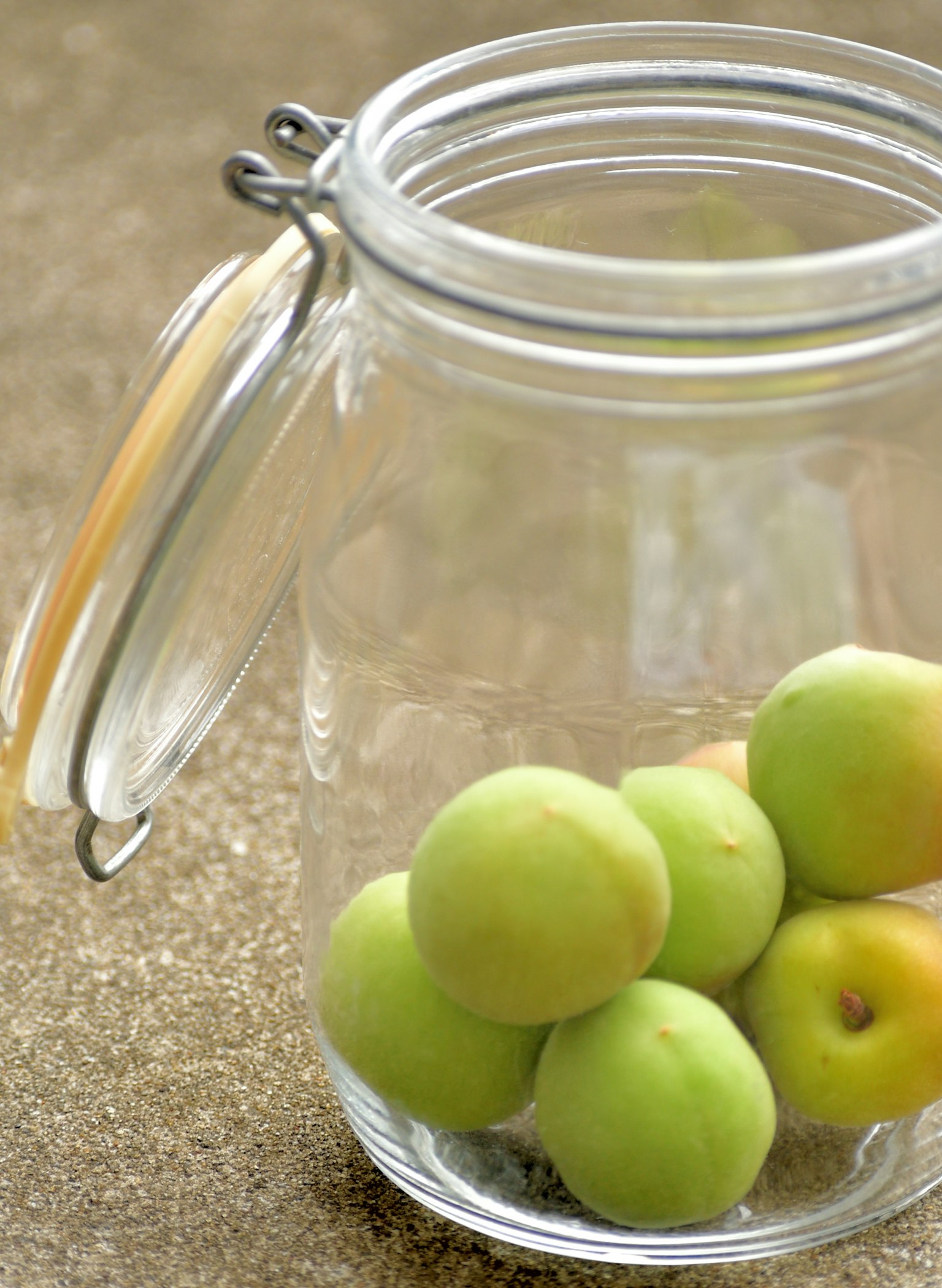 A clear glass jar containing green fruits