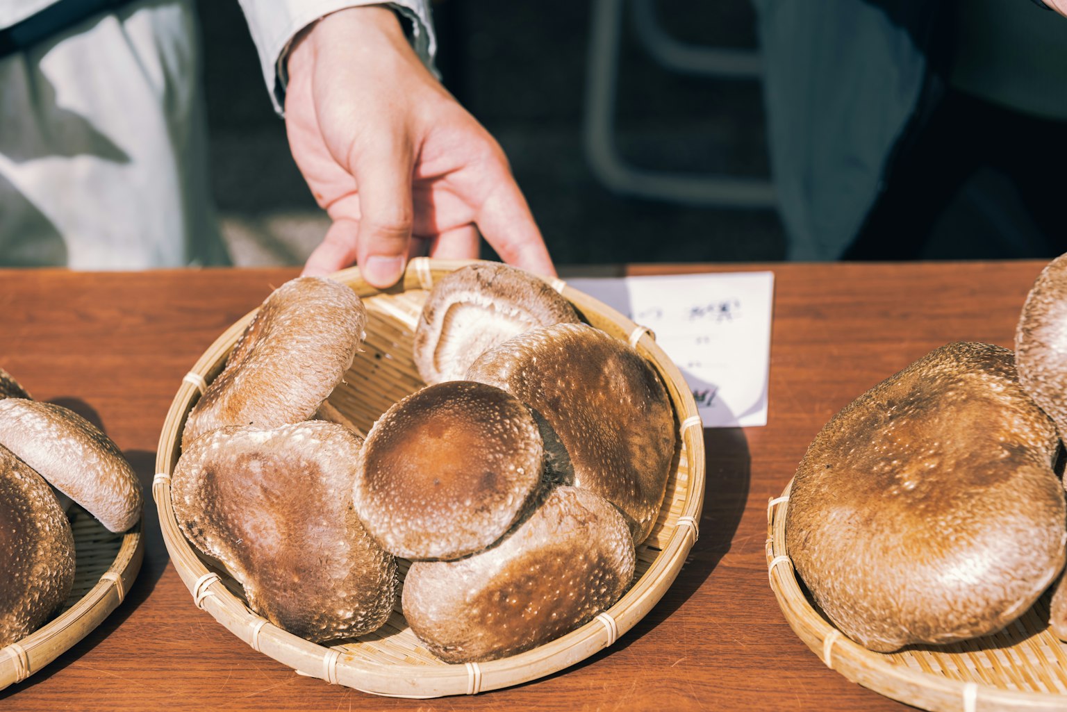 Una mano che tiene una ciotola di bambù piena di funghi shiitake