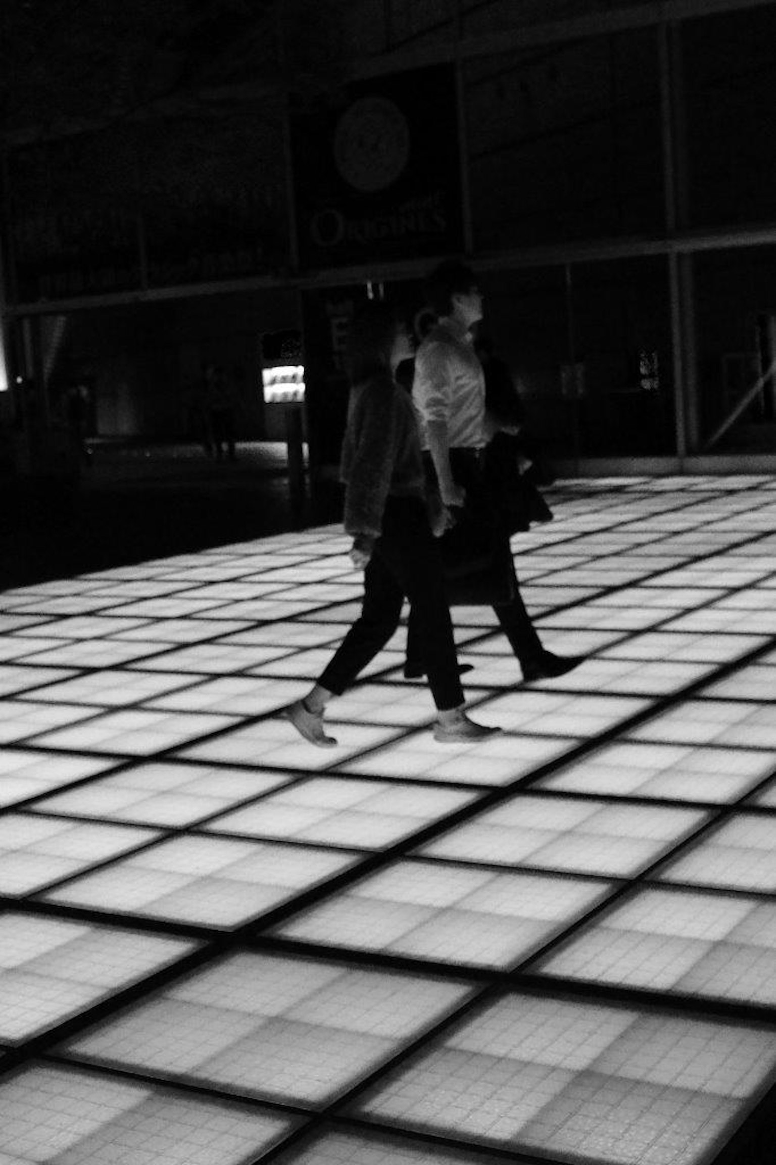 Due persone che camminano su un pavimento piastrellato luminoso in bianco e nero