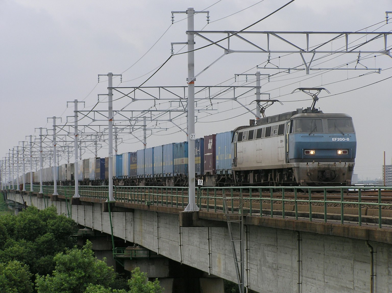 Un tren que tira vagones de carga en una vía elevada