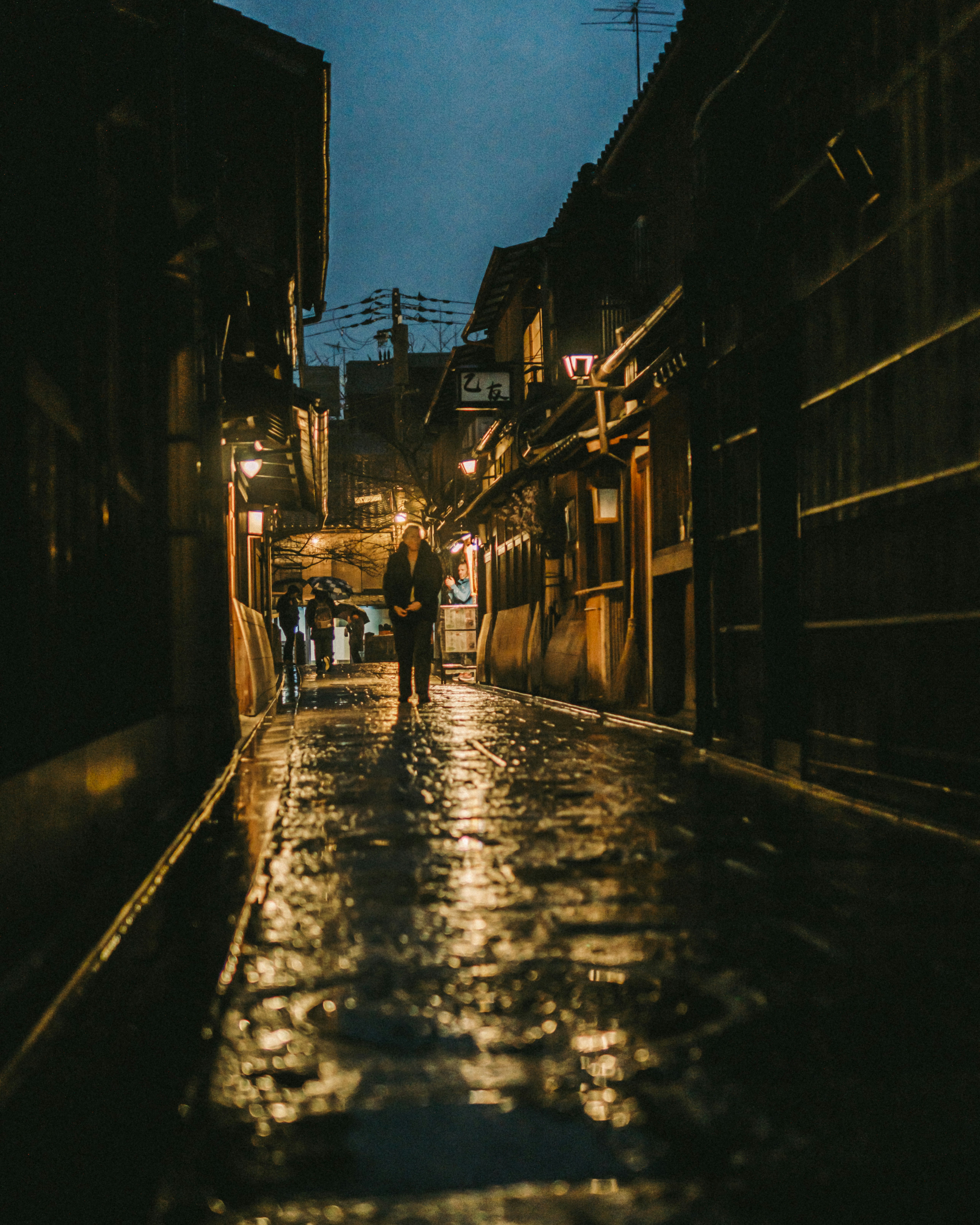 Lorong berkilau seperti cermin dengan lentera dan batu jalan basah