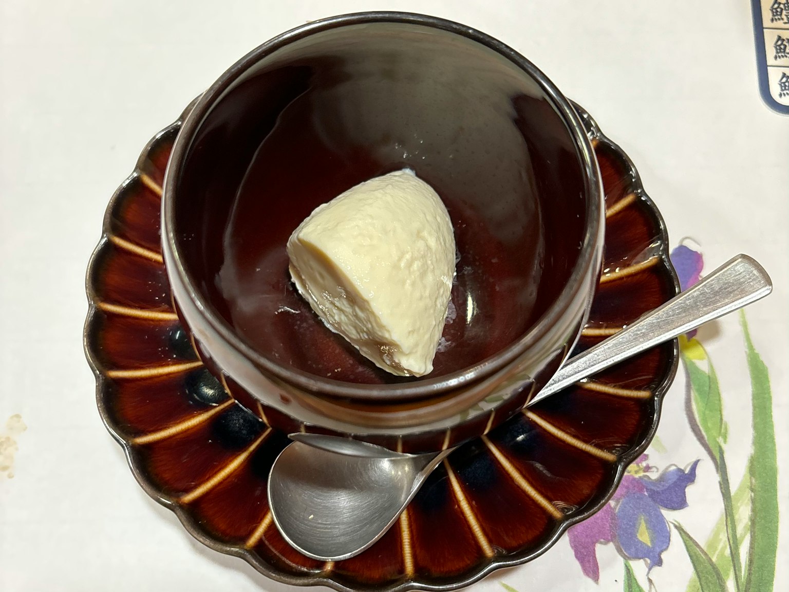 A black cup with a scoop of creamy ice cream on a decorative plate