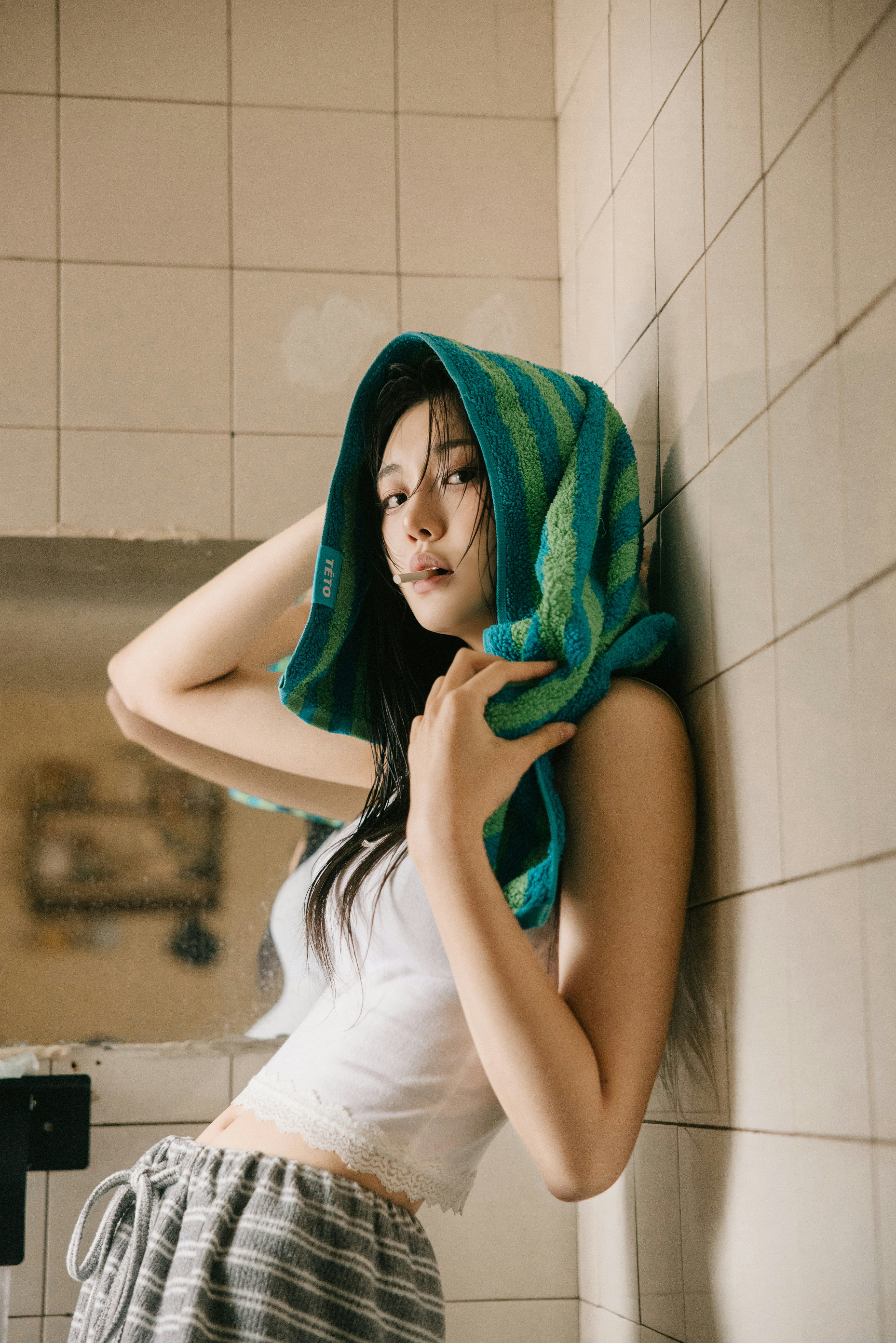 mujer relajada junto a una pared de azulejos con una toalla en la cabeza