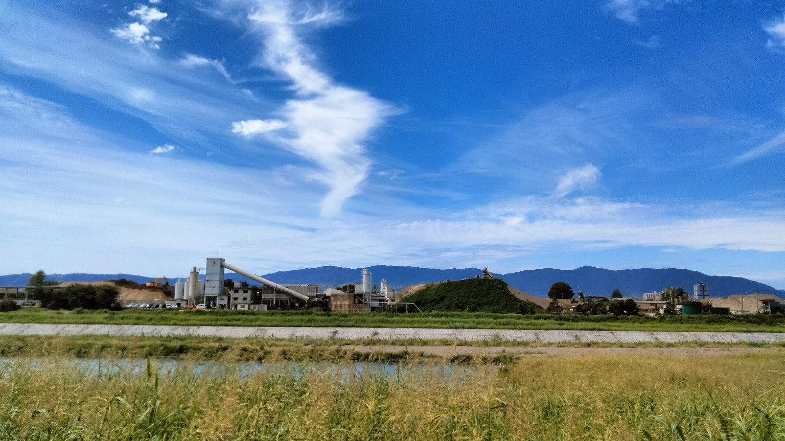 Campos verdes y edificios industriales bajo un cielo azul