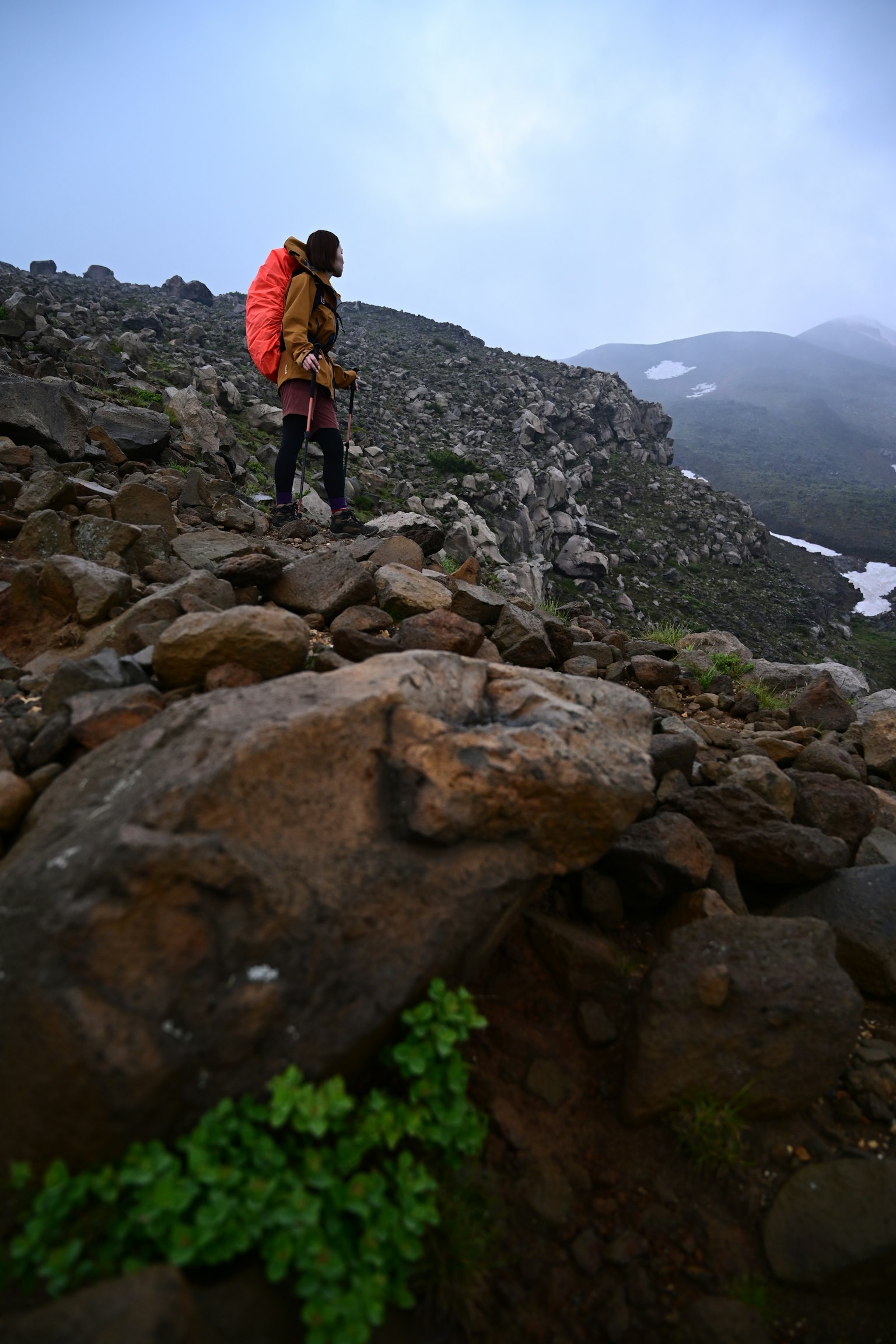 Escursionista che naviga su un terreno roccioso con sfondo di montagna nebbiosa