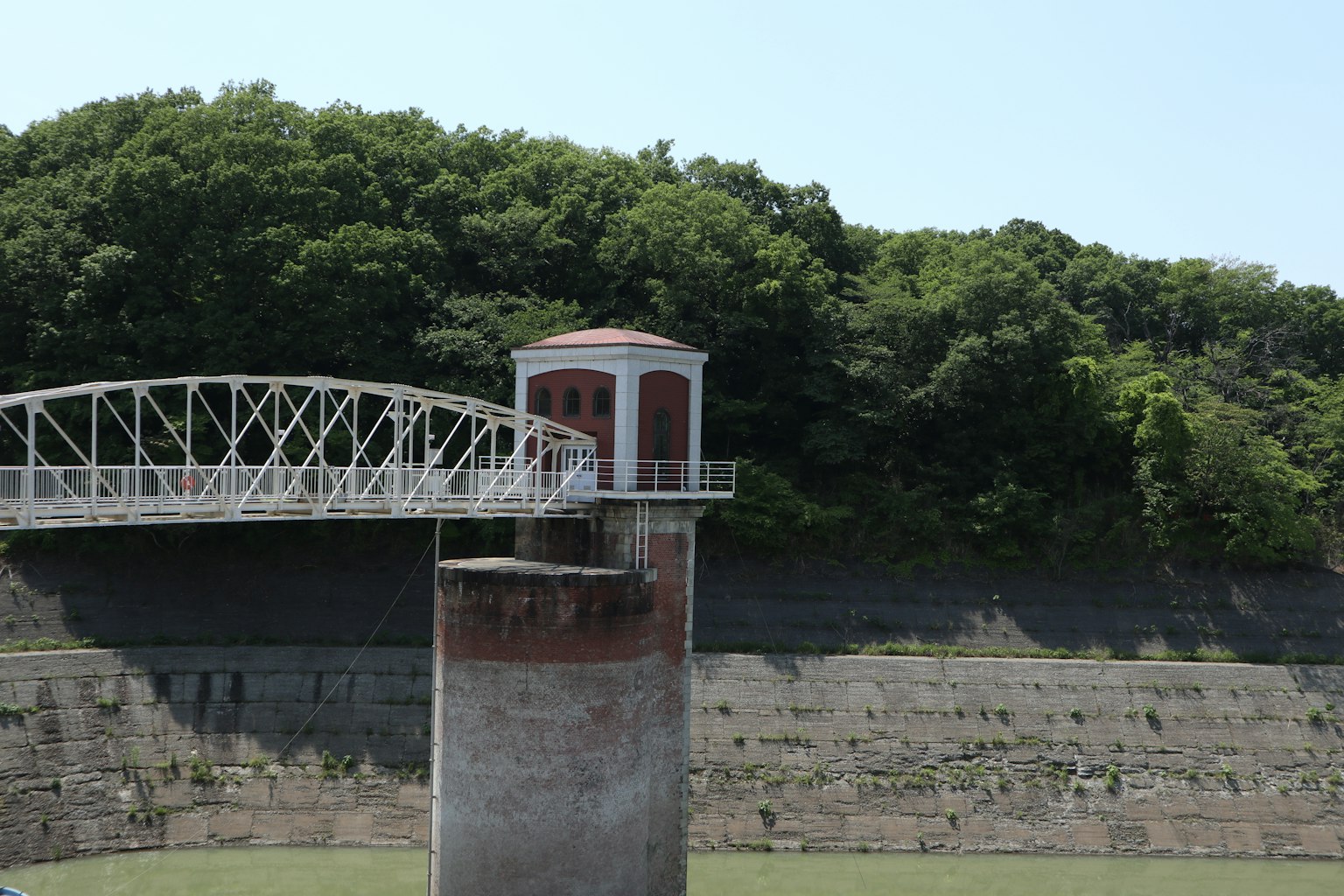 Ein Wassertor mit einem darüber liegenden Weg vor einer üppigen grünen Landschaft