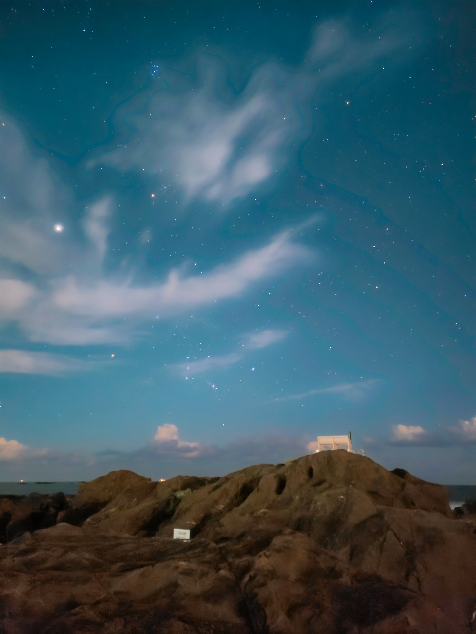 Collina rocciosa sotto un cielo stellato con nuvole