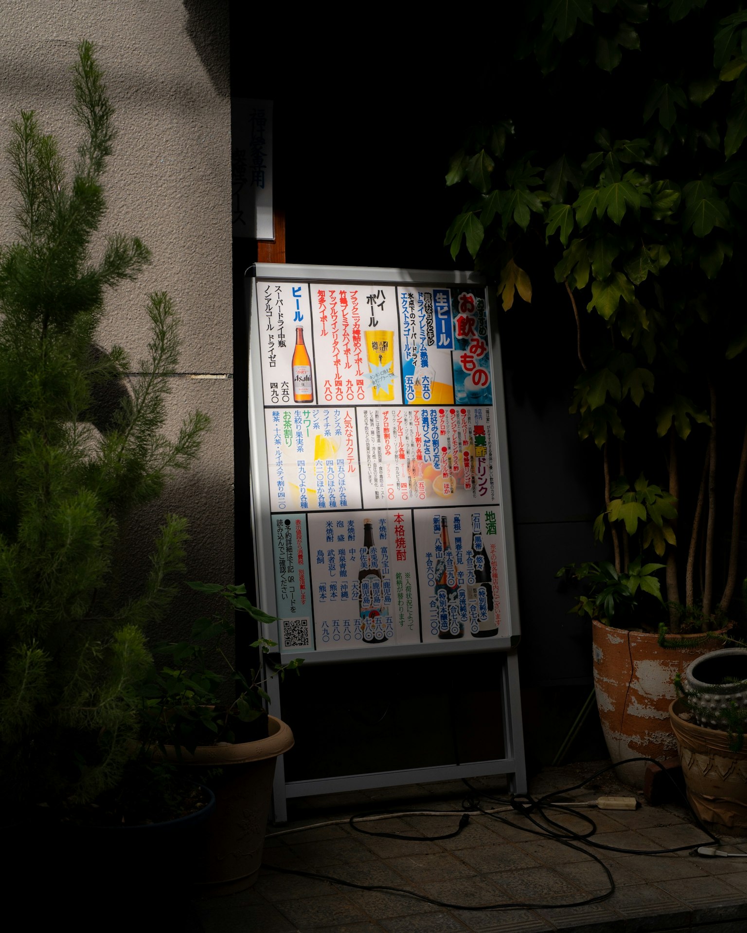飲食メニューが掲示された看板が植物の近くに立っている