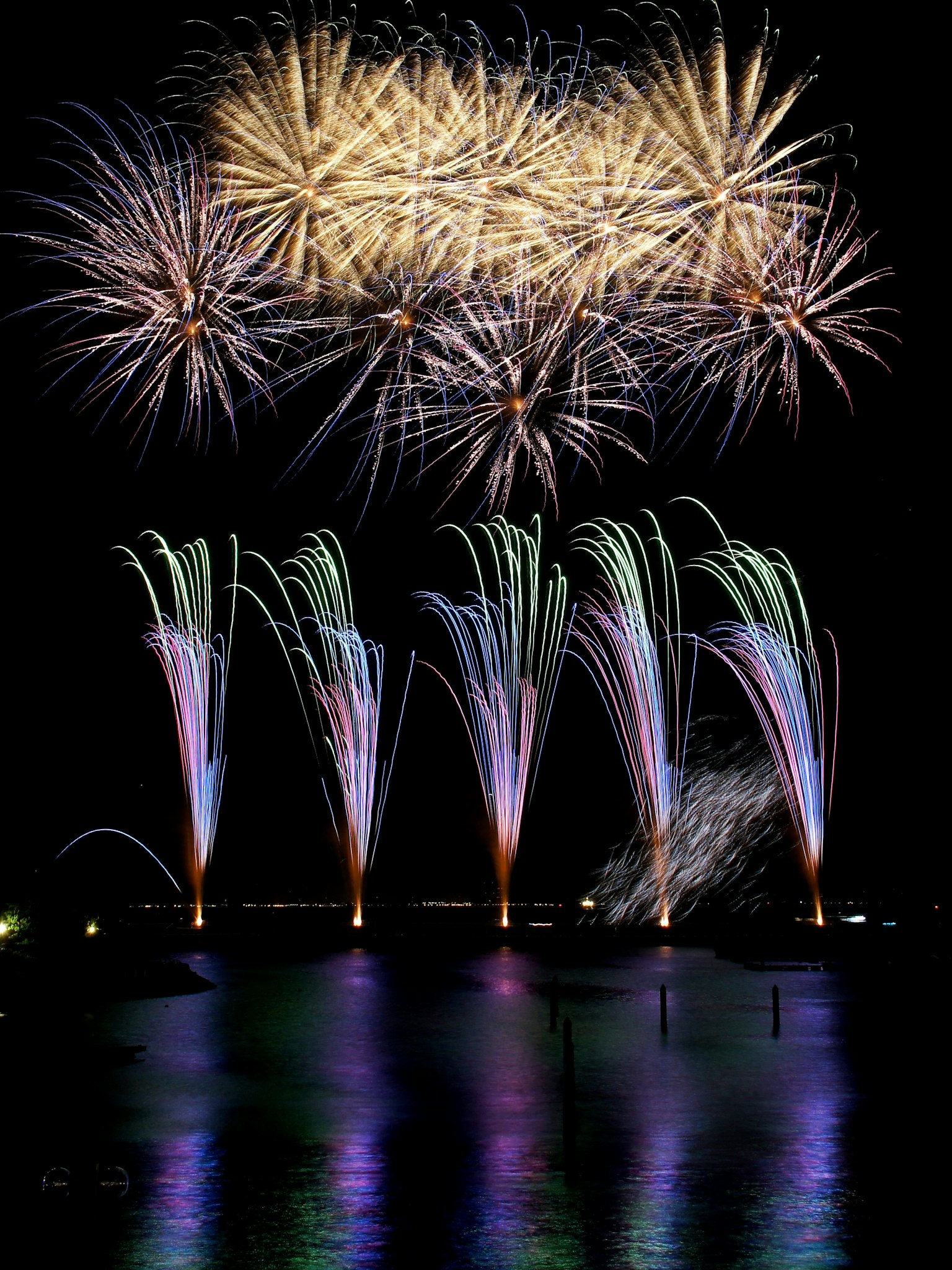 Spettacolo di fuochi d'artificio colorati sopra l'acqua con fontane vivaci