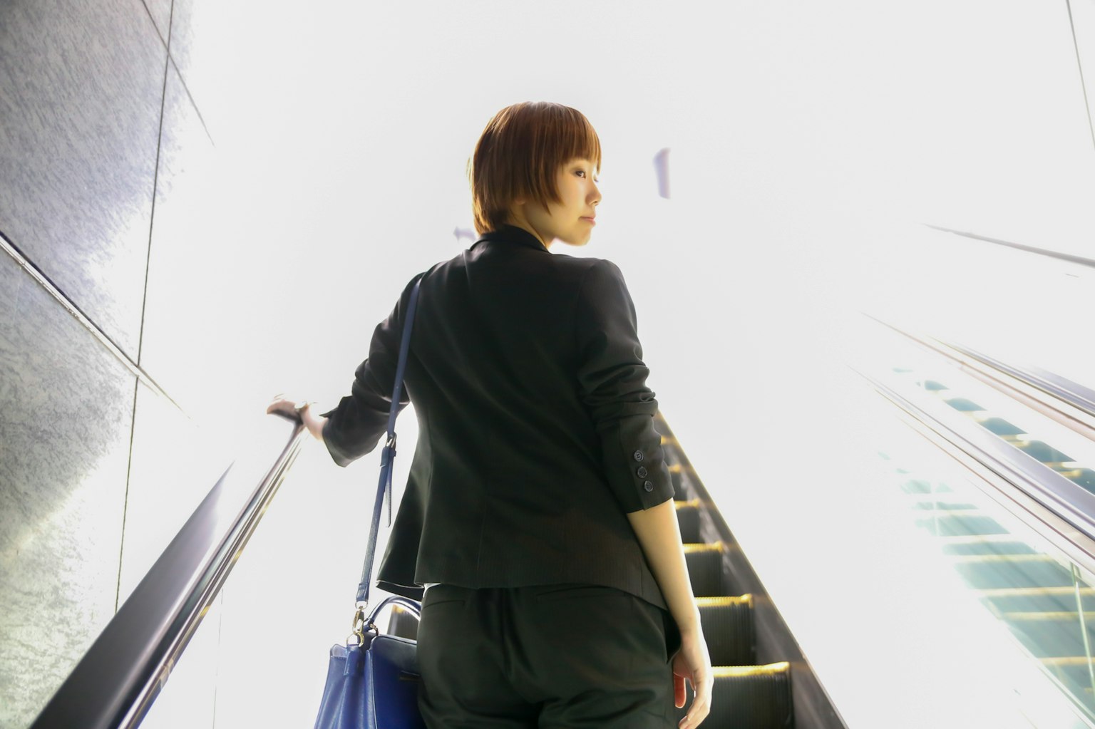 Femme montant un escalator dans une lumière vive