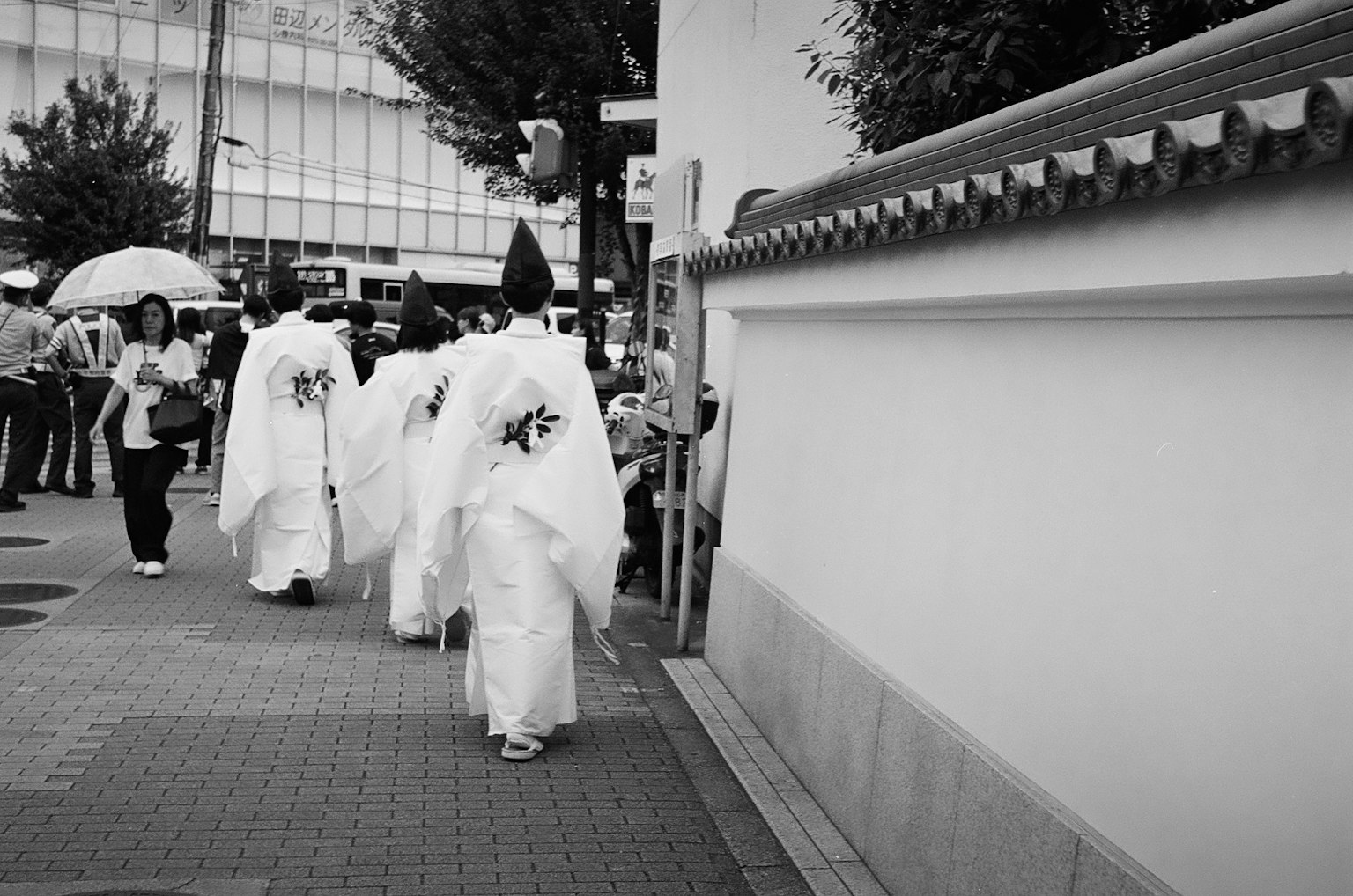 ผู้คนในชุดขาวเดินอยู่บนถนนในเมือง