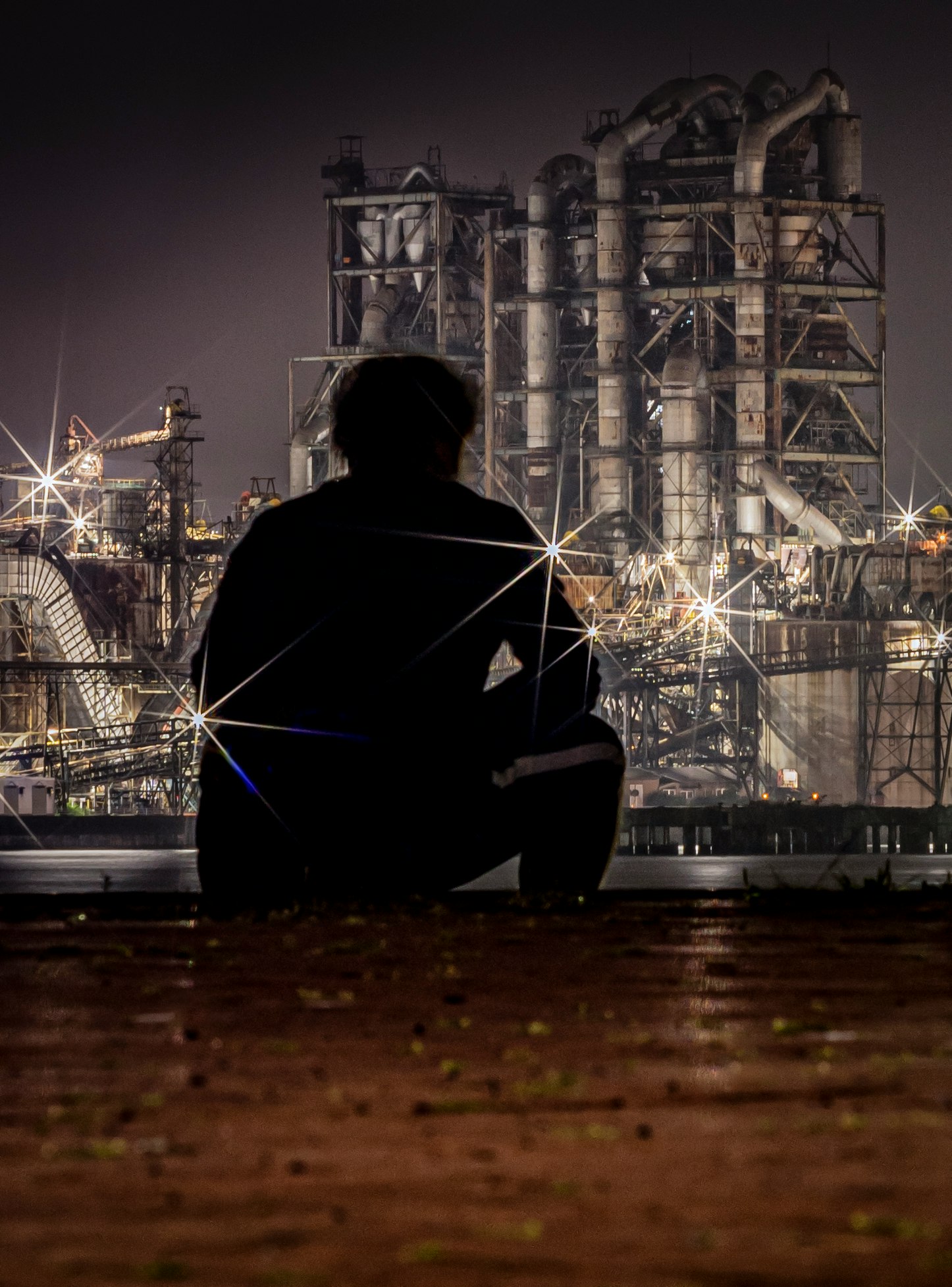 A person sitting in front of an industrial night skyline
