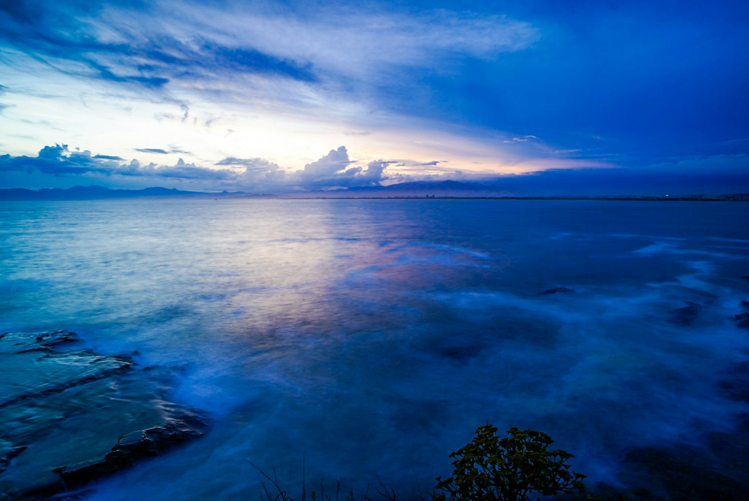 美麗的藍色海洋上方的日落景色，伴隨著雲彩