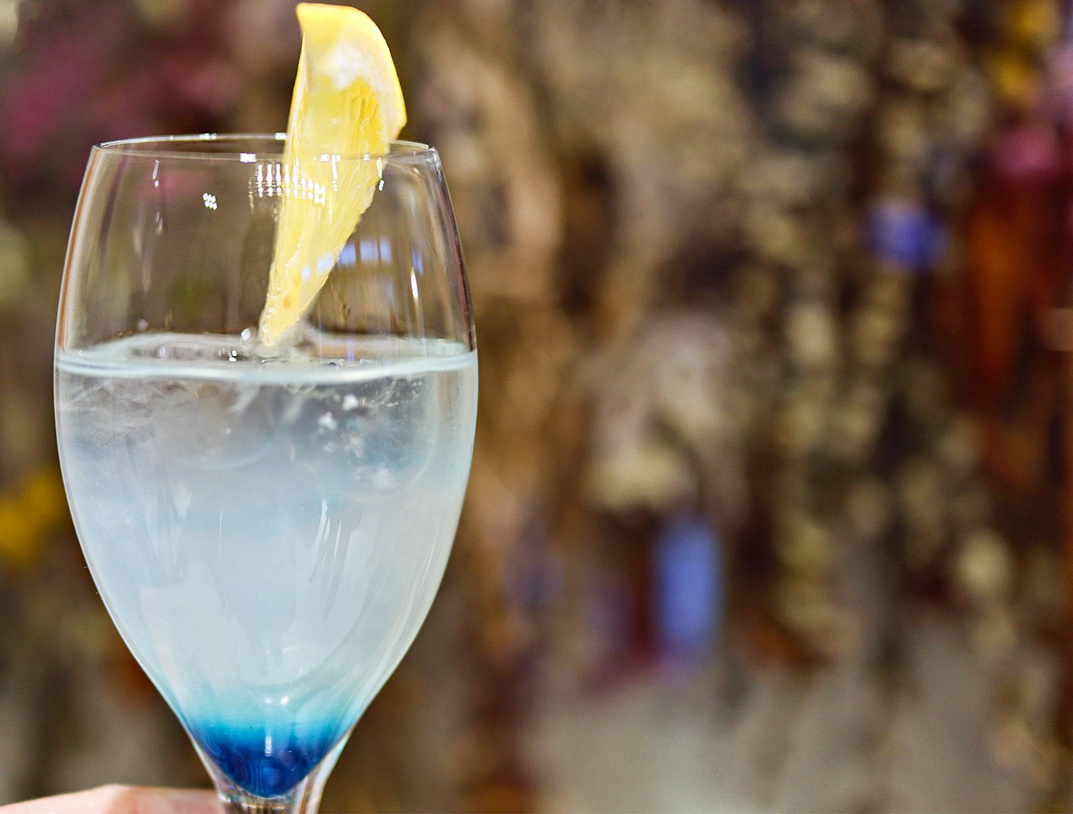 Un vaso de cóctel con una bebida azul degradada decorada con una rodaja de limón