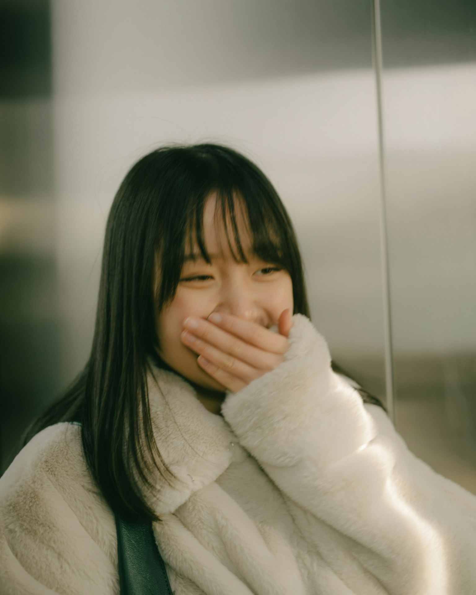 ผู้หญิงยิ้มปิดปากด้วยมือ