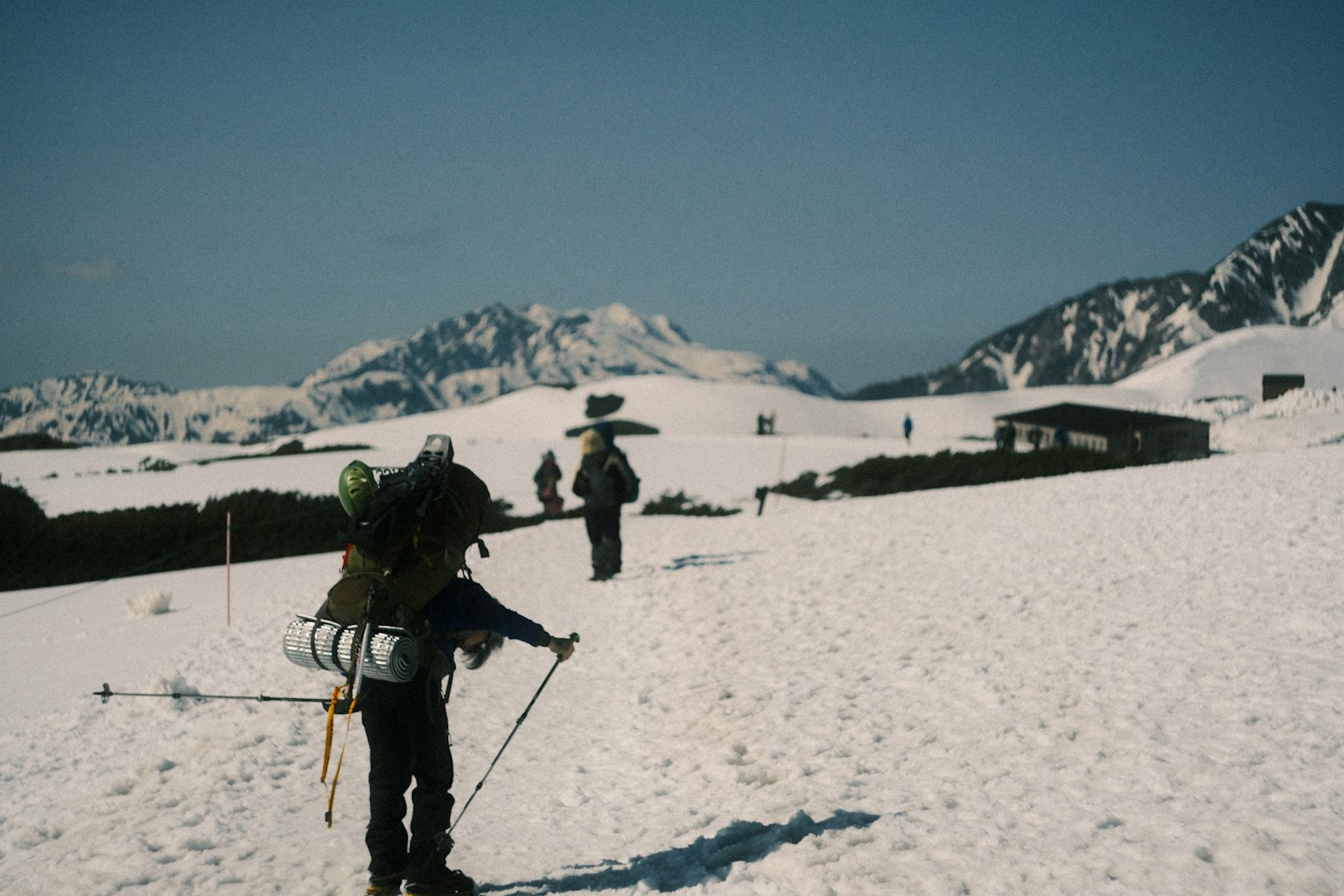 Hikers walking on a snowy landscape with mountains in the background