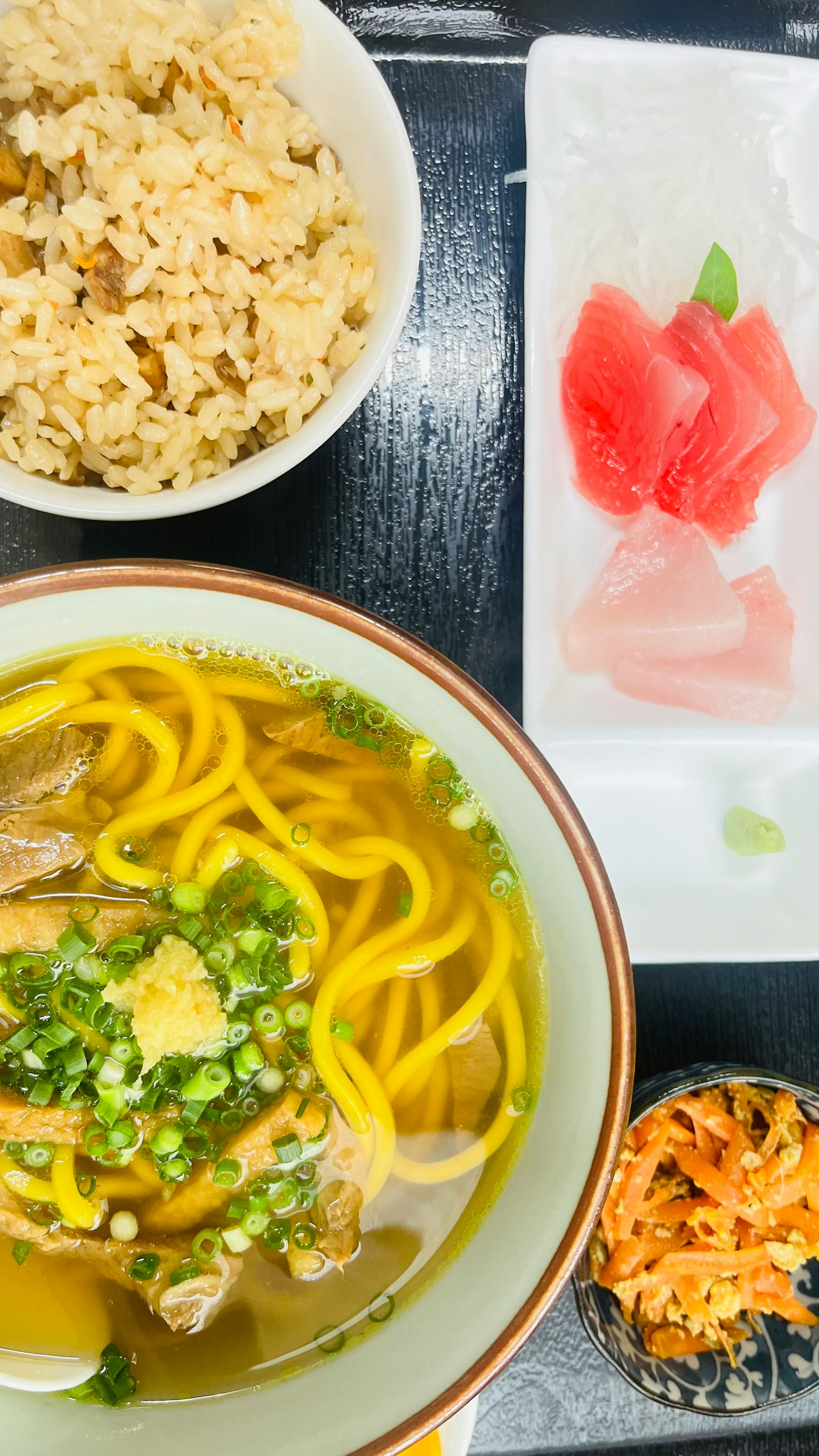 Un pasto con ramen, riso integrale, sashimi e un'insalata di contorno