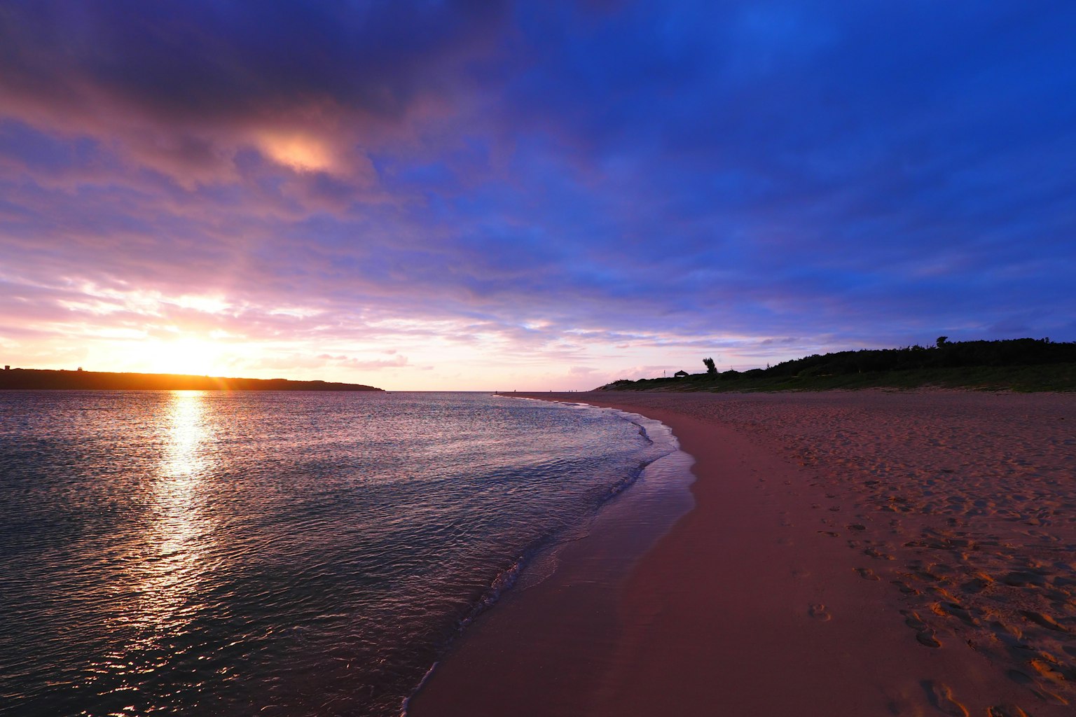 พระอาทิตย์ตกที่สวยงามเหนือชายหาดที่เงียบสงบพร้อมคลื่นเบา
