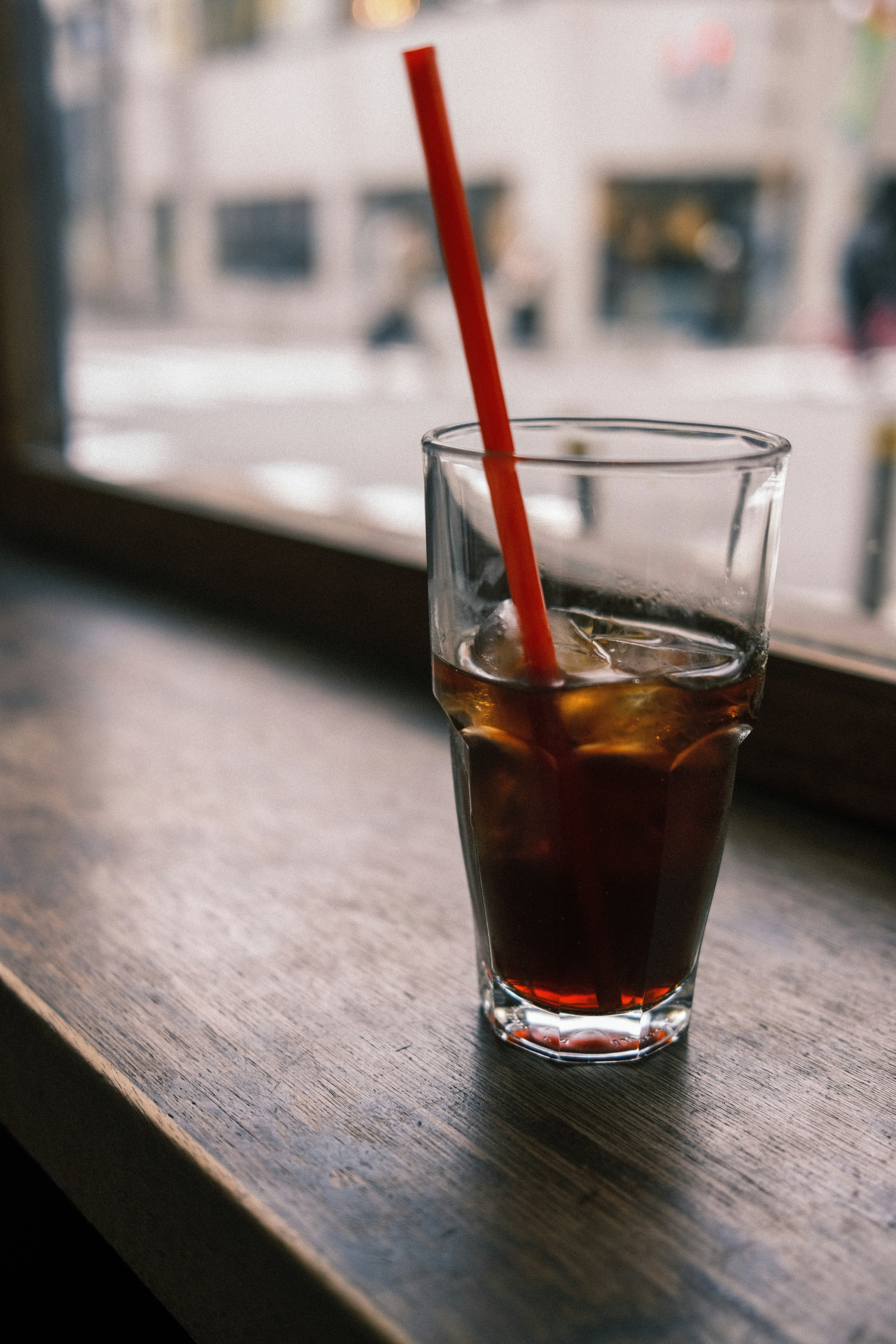 木のテーブルに置かれたアイスコーヒーとストロー